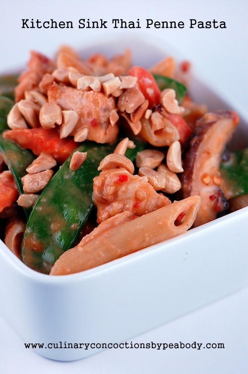 White bowl filled with the pasta sticking out as well as the veggies and chicken pieces all covered in chopped peanuts.
