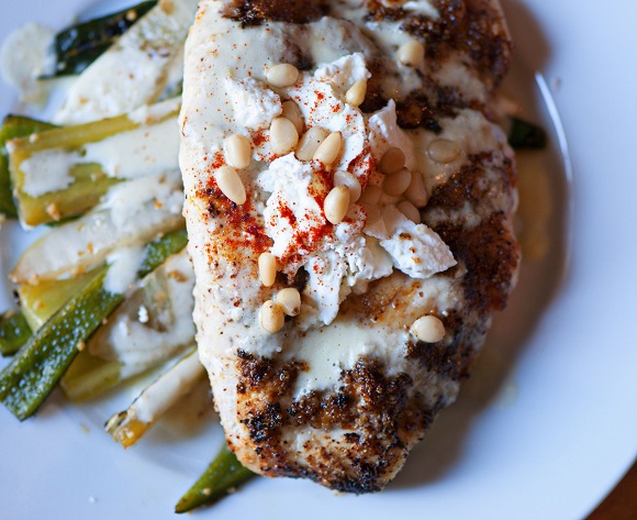 Overhead shot of the Tomatillo Beurre Blanc Chicken sitting on top of the peppers on a plate. 