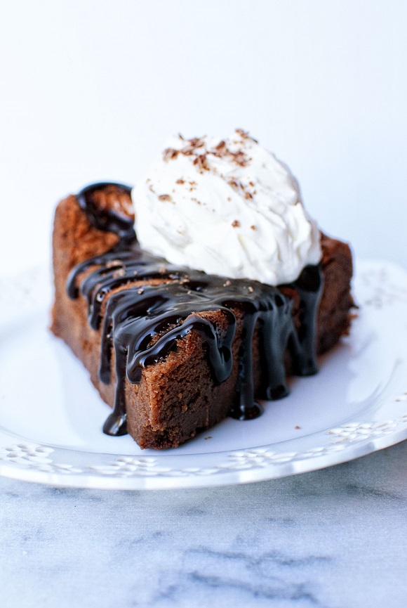 Close up of Chocolate Flourless Cake with chocolate sauce dripping down.