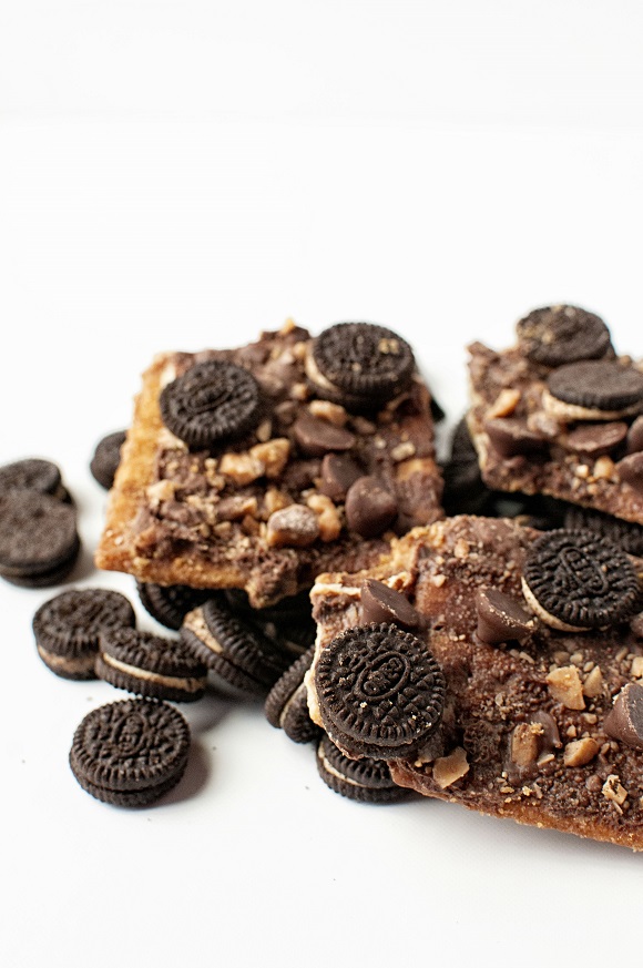 Close up of three pieces of cracker toffee with extra Oreos scattered around