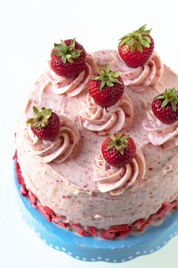 Three quarter shot of Strawberry Shortcake Layer Cake on a blue cake stand.