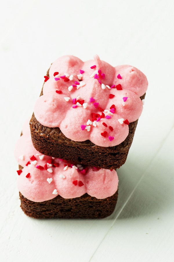 Two Cinnamon Brownies with Red Hot Infused Buttercream Frosting stacked on each other. 