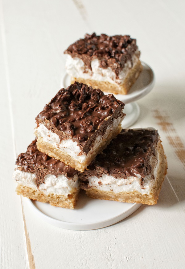 Three Peanut Butter Marshmallow Crunch Bars on a small plate with one more on a tiny cupcake platter behind it.