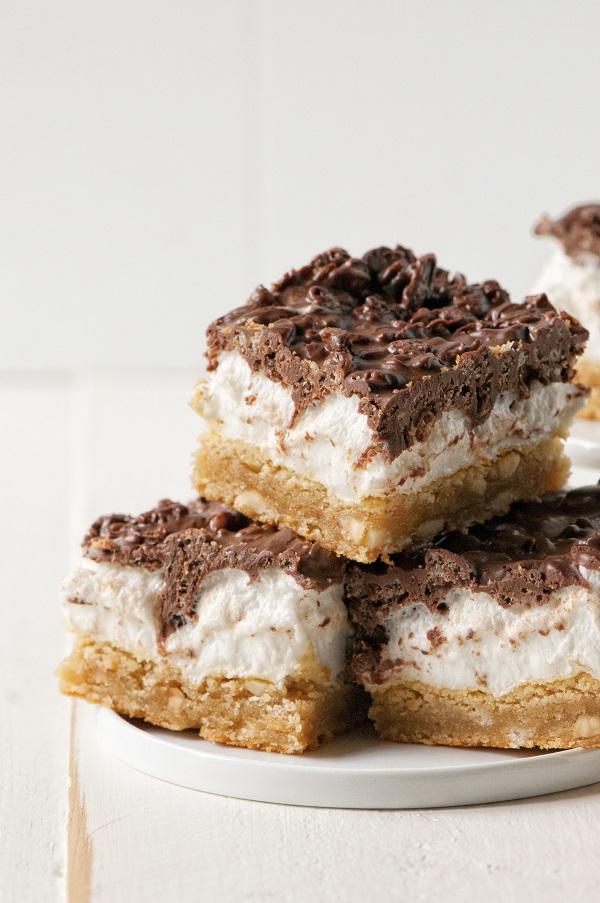 Several Peanut Butter Marshmallow Crunch Bars stacked on top of each other on a plate. 