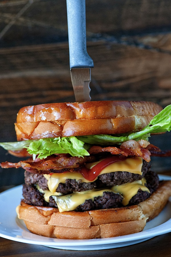 Grilled Cheese Double Bacon Cheeseburger with knife holding it together. 