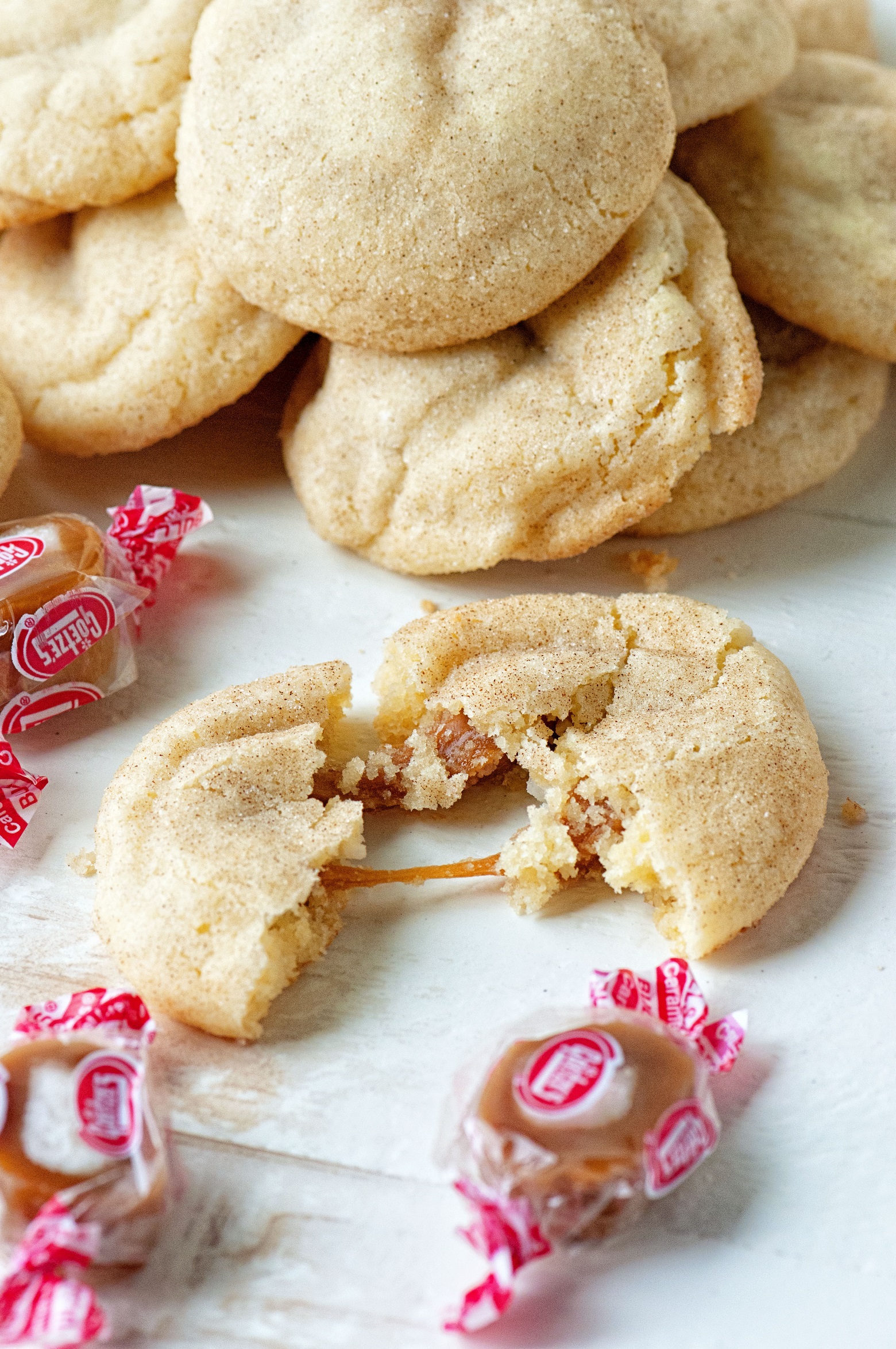 Snickerdoodle cookie torn apart with caramel being pulled. 