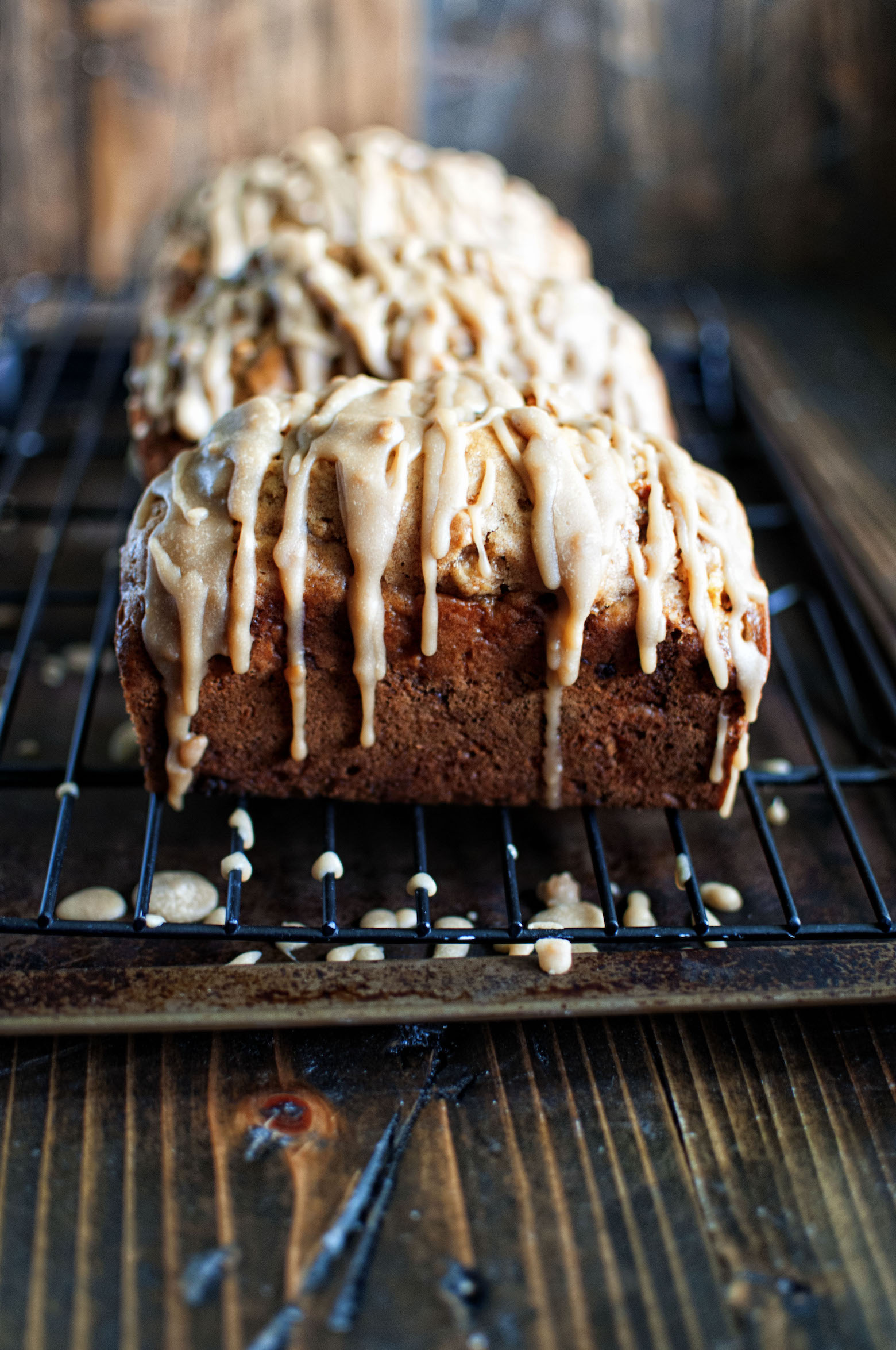 Side view of Mini Apple Bread with Caramel Bourbon Glaze on a wire rack with glaze dripping down.