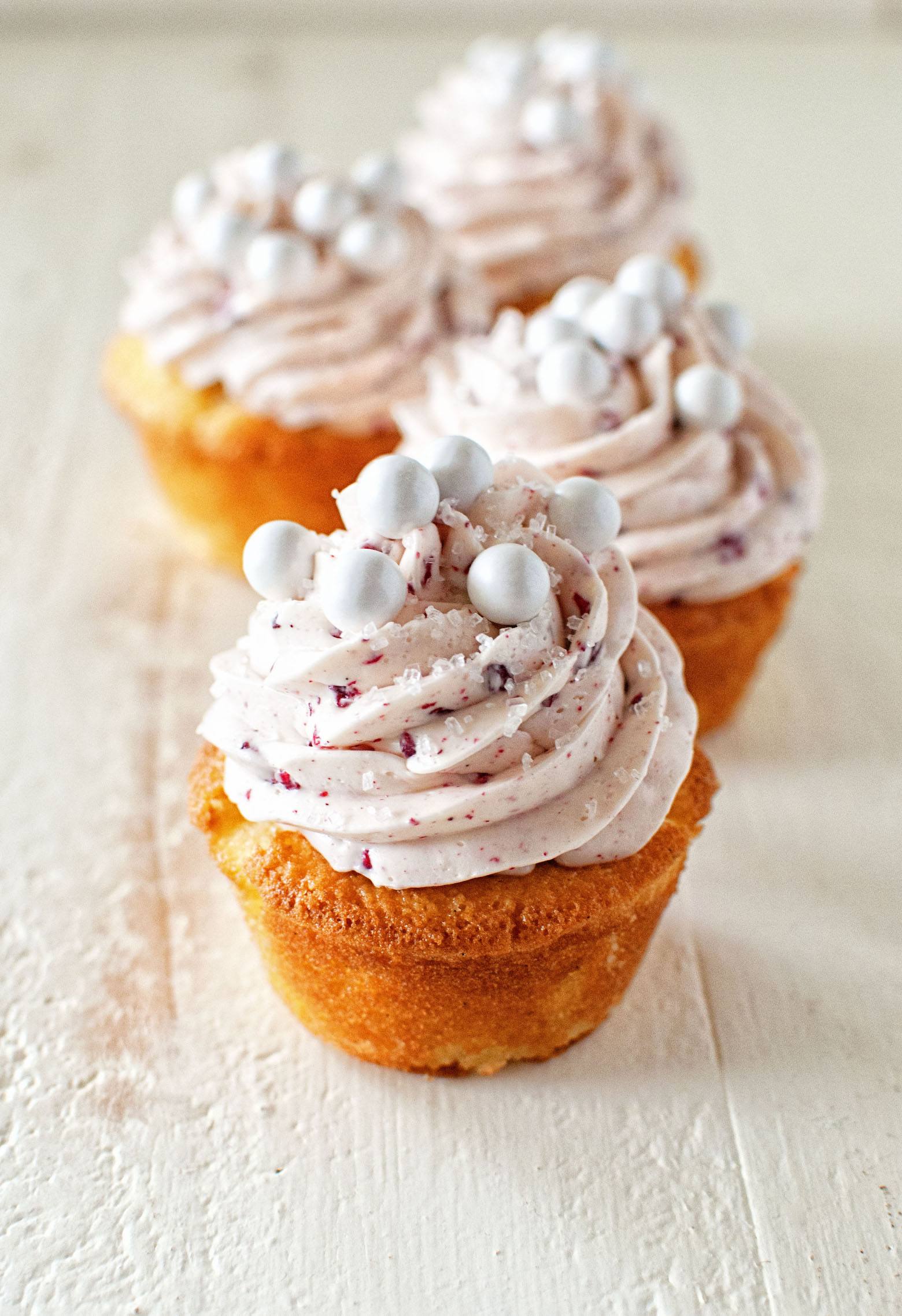 Four Raspberry Mimosa Cupcakes in a row front to back with focus on the first cupcake.
