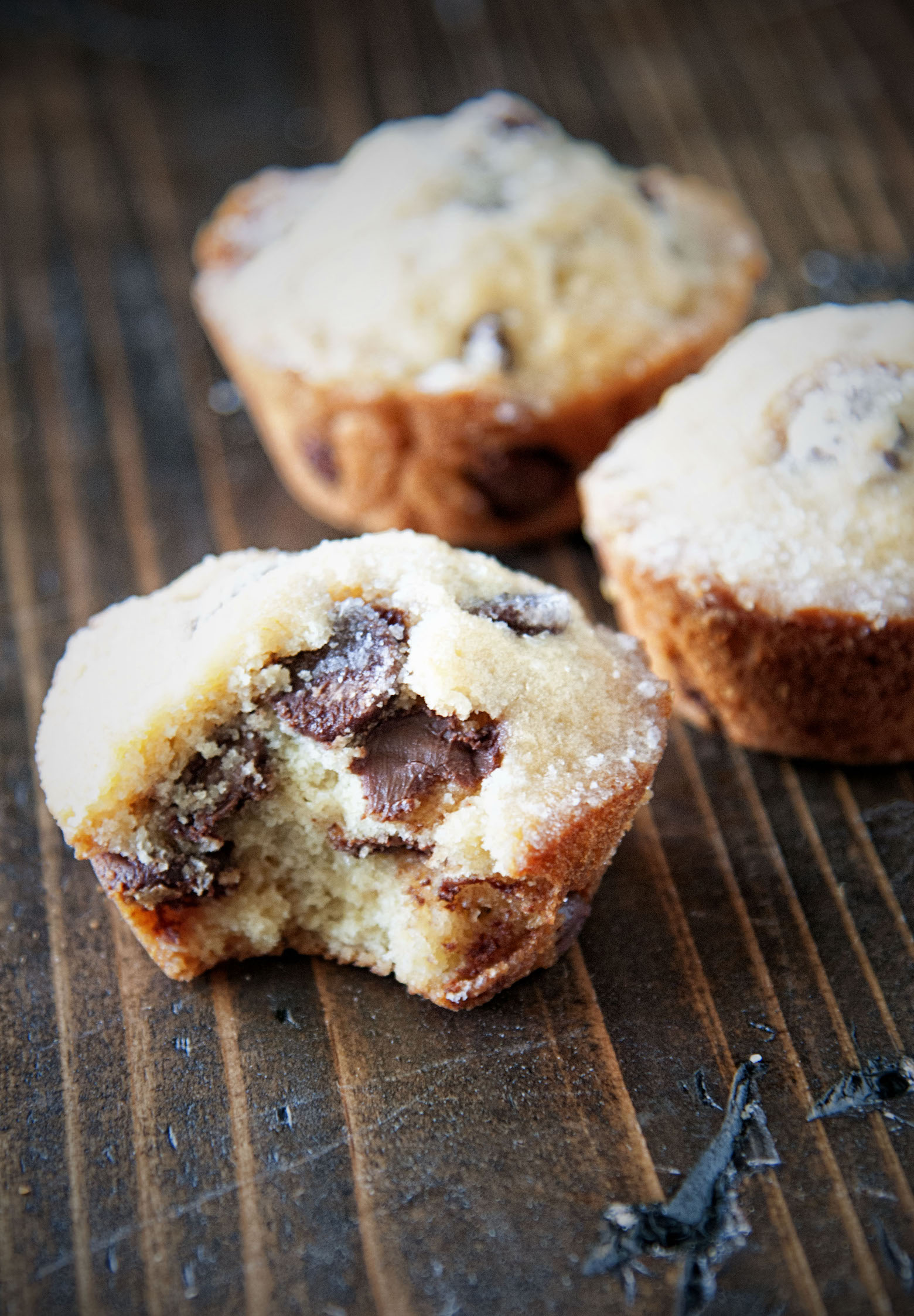 Three Whiskey Glazed Chocolate Chip Muffins with the first one having a bite in it. 