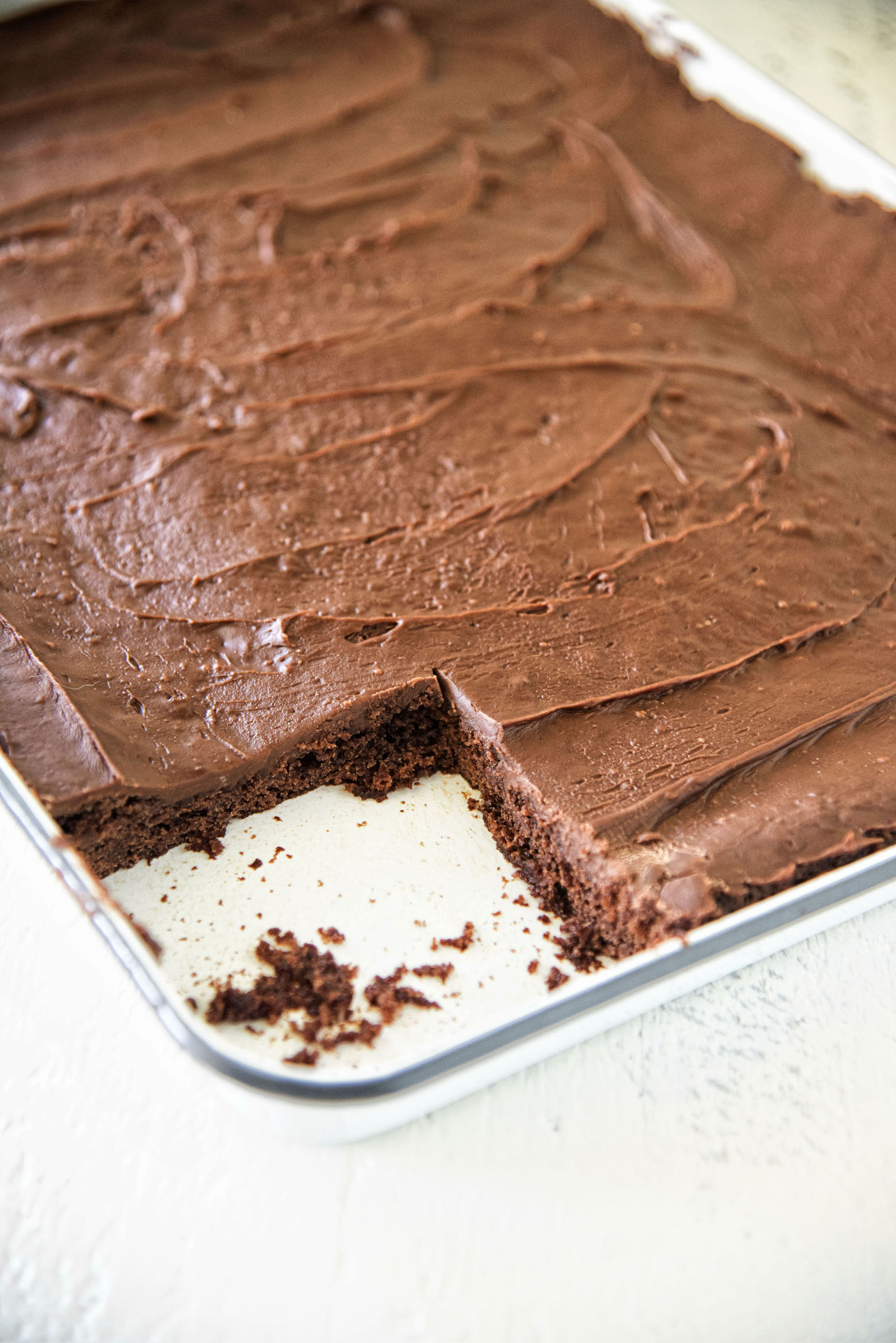 Jack and Coke Texas Sheet Cake in pan with piece missing.