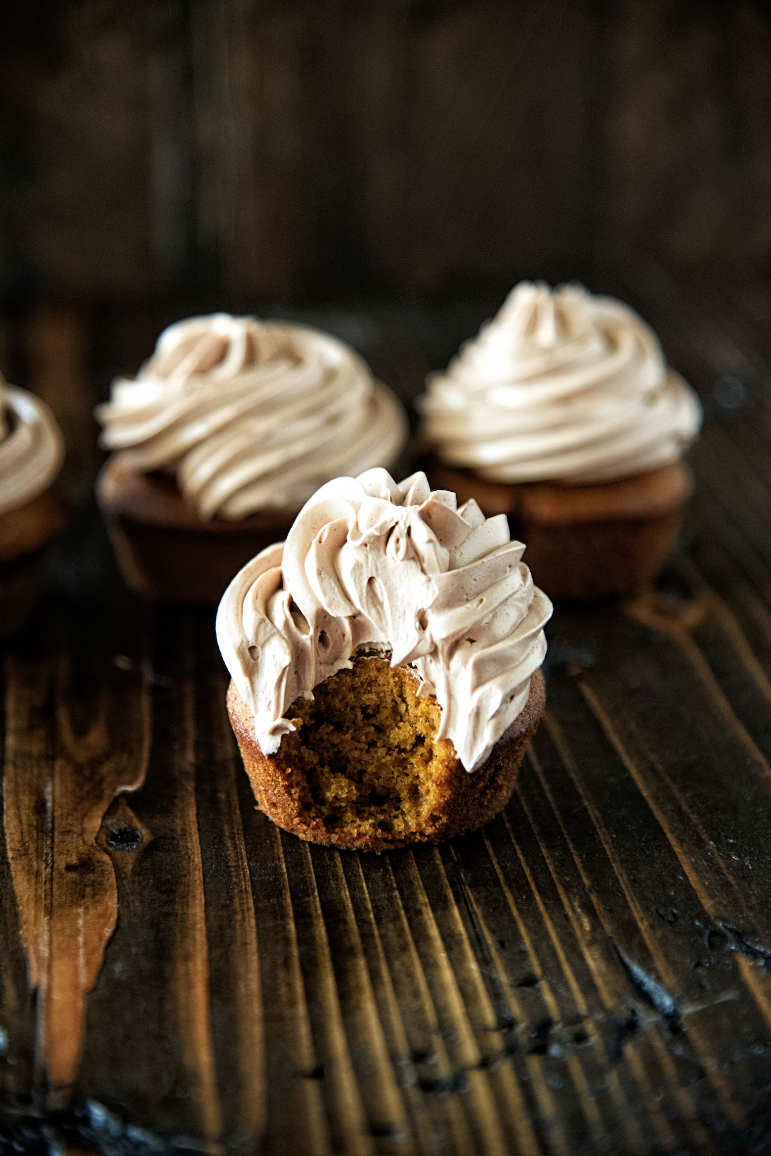 Chocolate Cinnamon Frosted Pumpkin Cupcakes with bite taken out of one