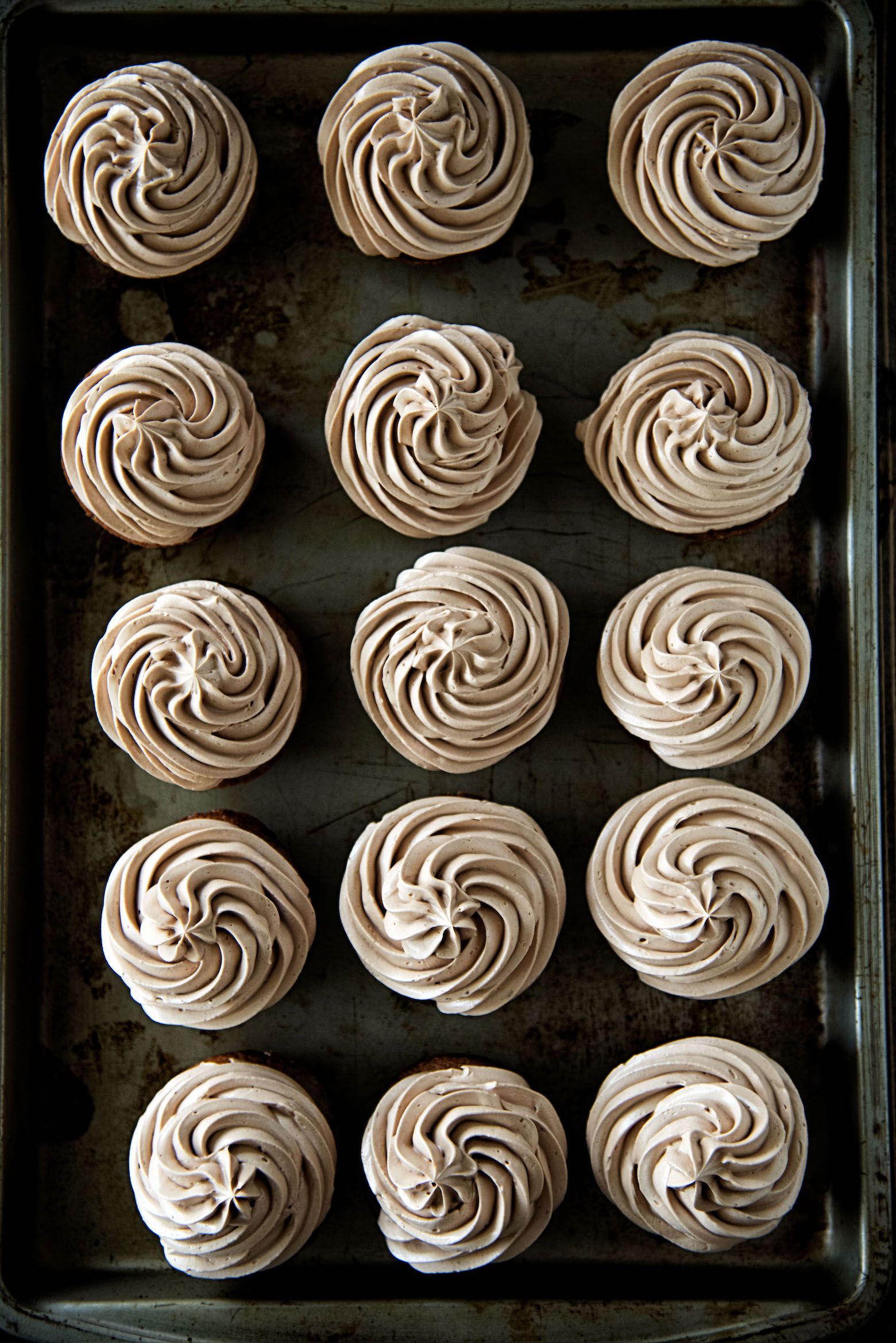 Overhead shot of Chocolate Cinnamon Frosted Pumpkin Cupcakes on a sheet pan.