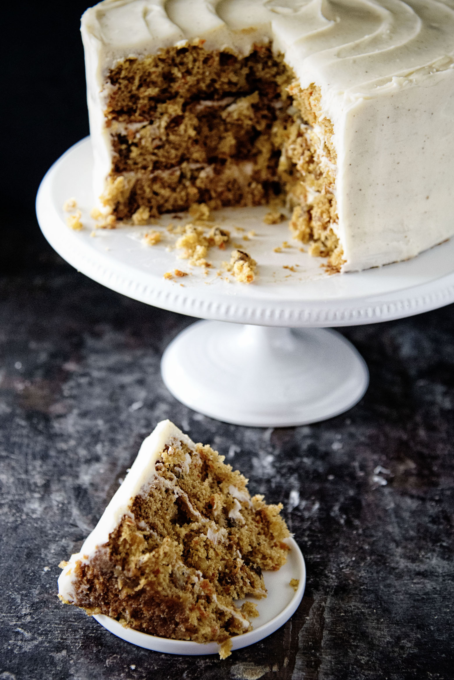 Slice of Chai Spice Brown Butter Carrot Cake in front of cake on cake stand.