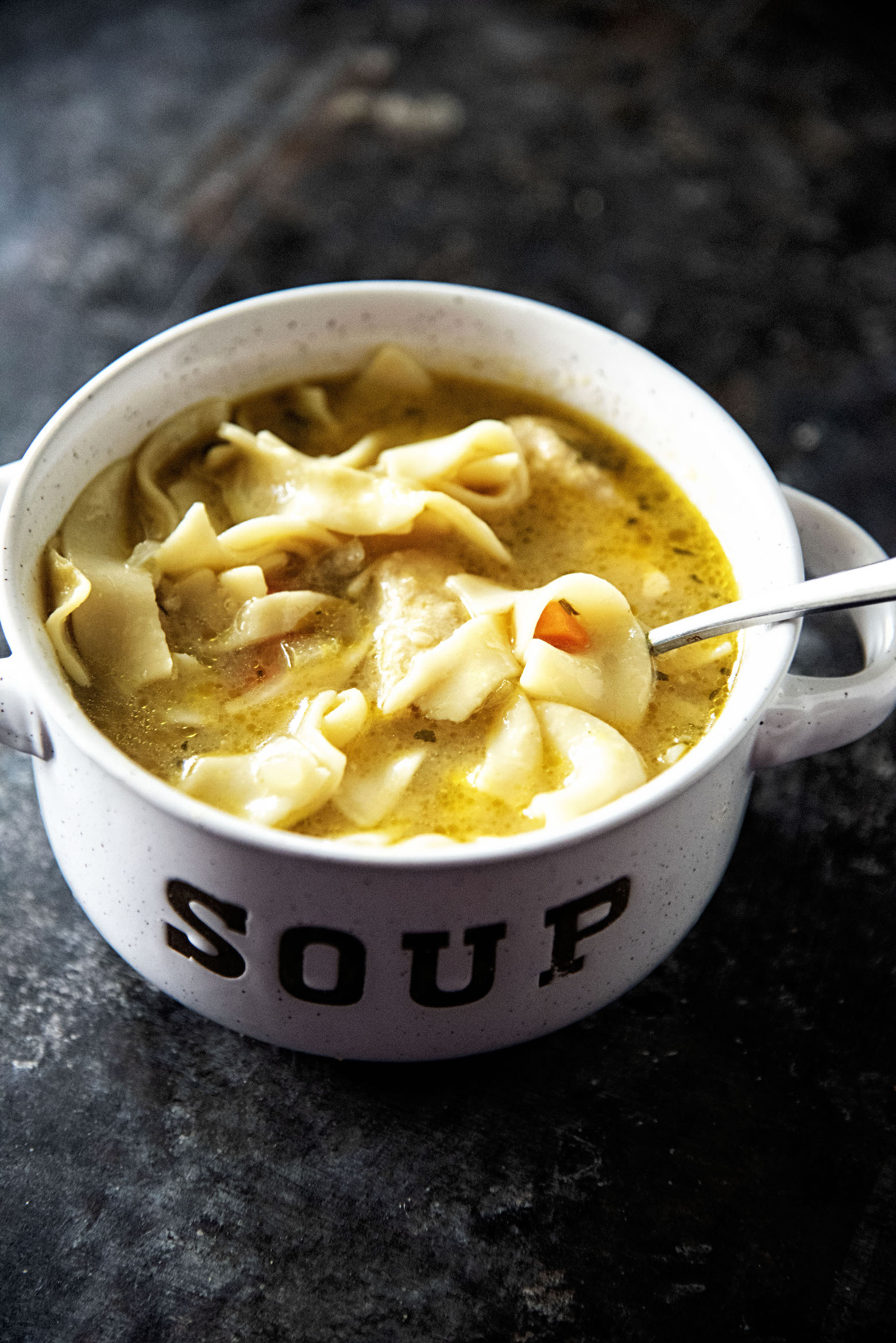 Bowl of Chickenless-Chicken Noodle Soup with spoon lifting up a noodle.