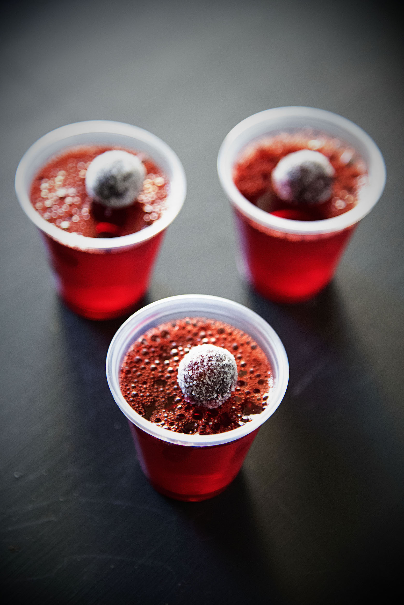 Three Cranberry Orange Jello Shots with sugared cranberries on top. 