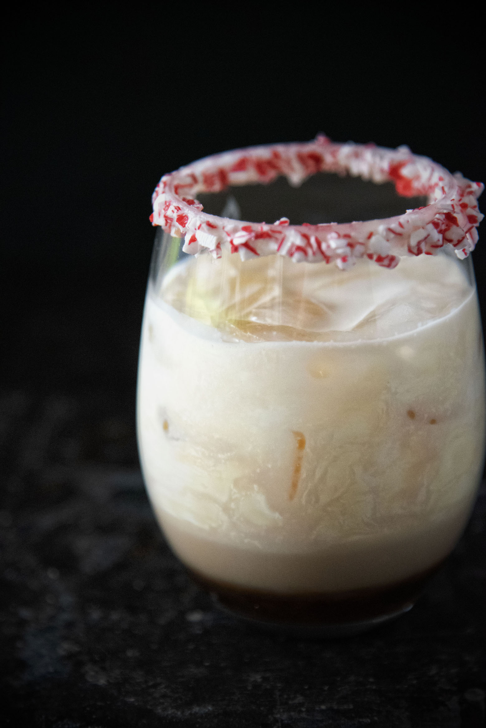 Side view Peppermint White Russian with the focus on the swirl of the heavy cream mixing with the Kahlua. 
