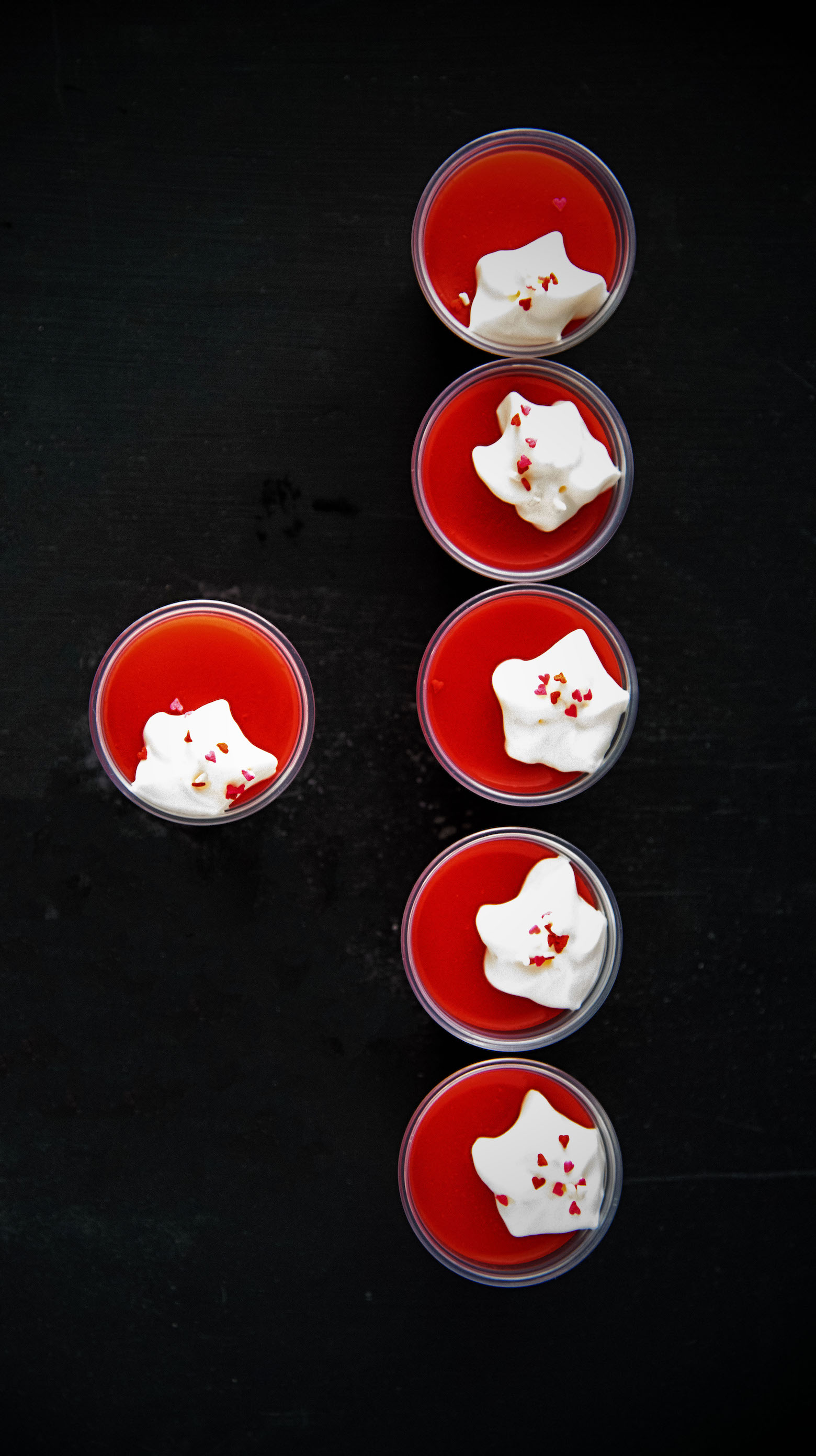 Overhead shot of Strawberry Malted Milk Jello Shots all in a row with one shot off to the side.