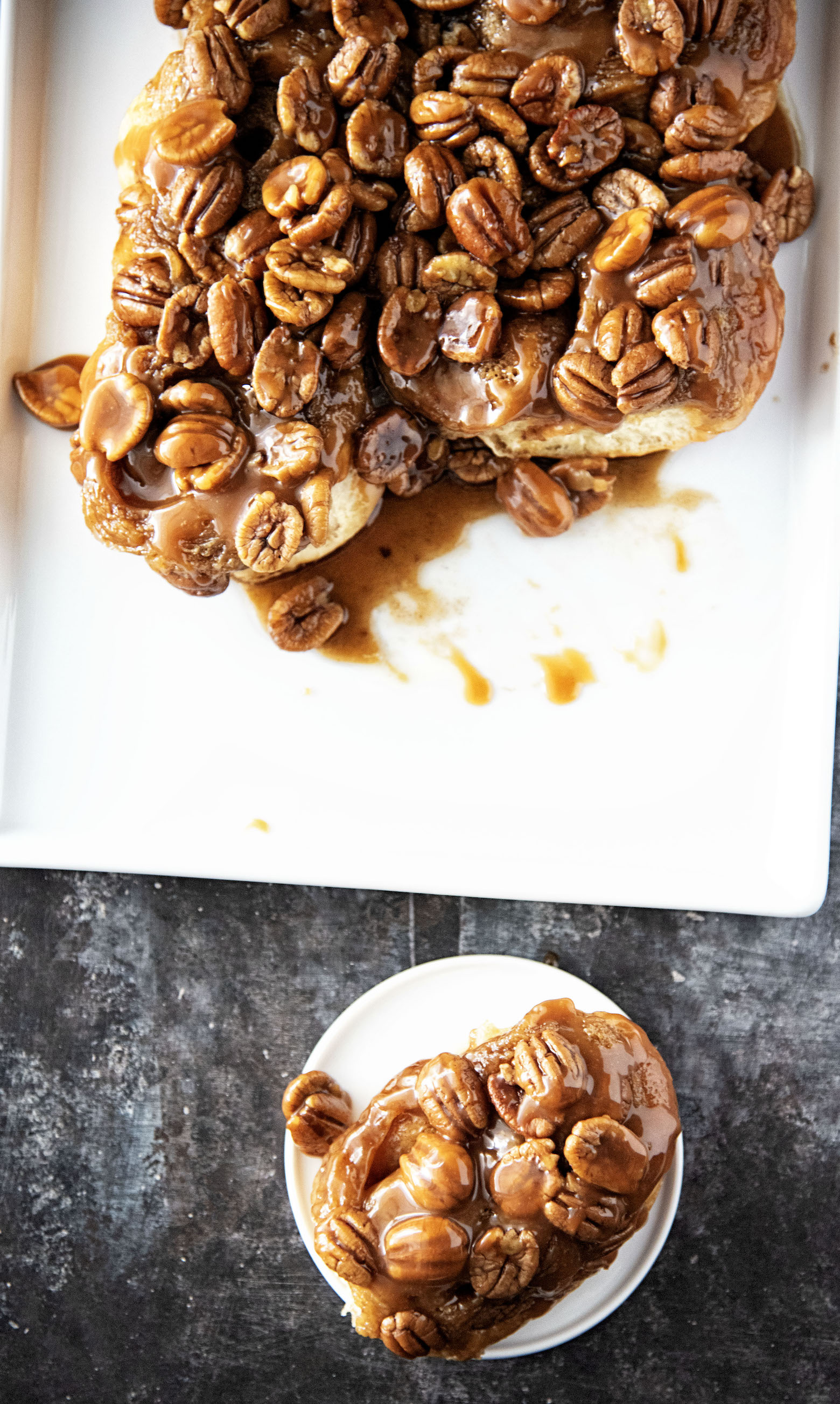 Overhead shot of Whiskey Butterscotch Pecan Sticky Buns with one of the buns on a plate.