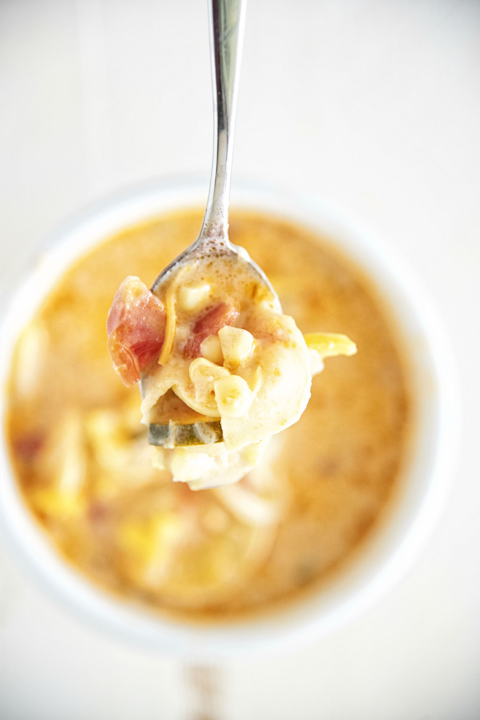 Close up of Cheese Tortellini Zucchini Corn Soup on a spoon.