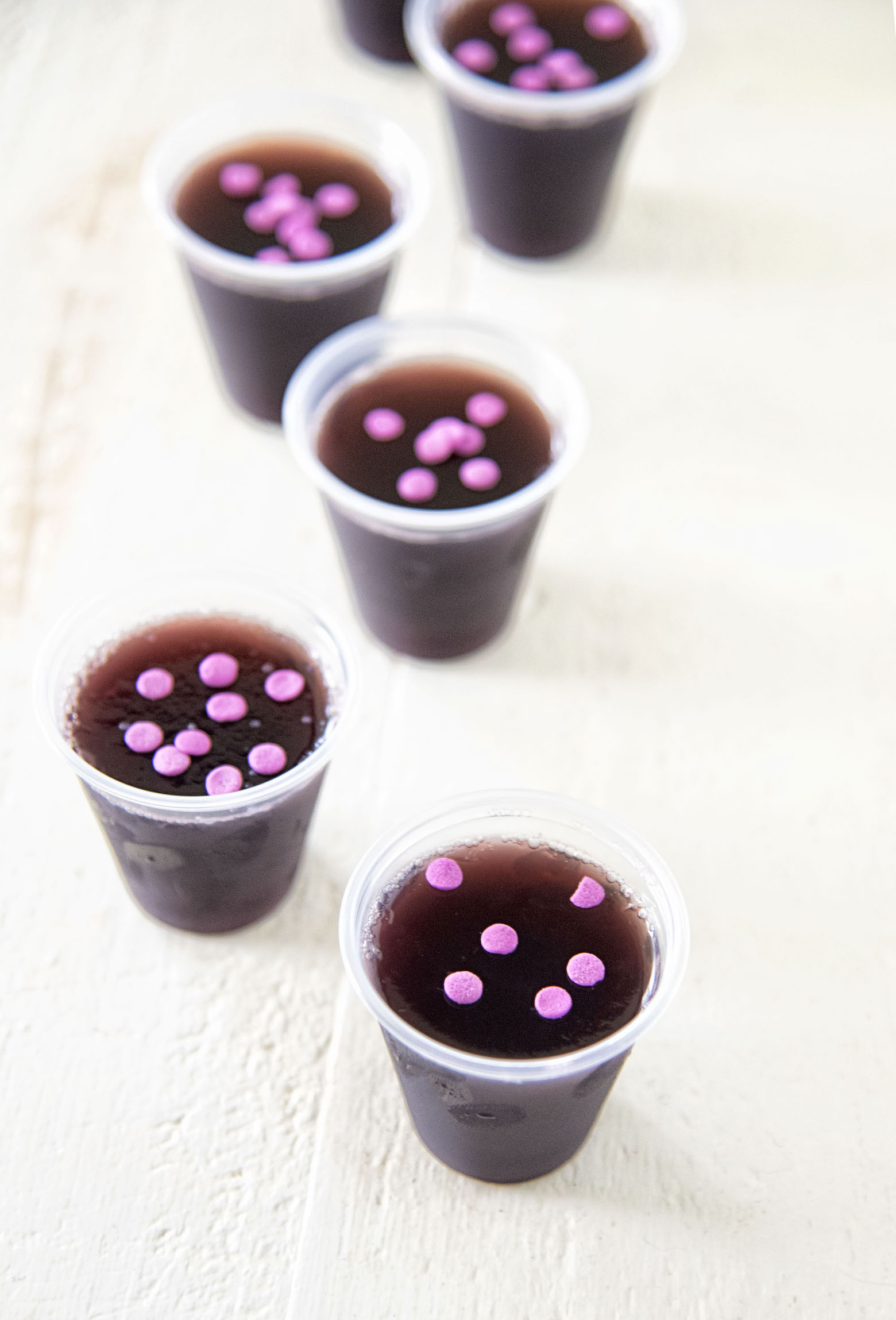 Grape Limeade Vodka Jello Shots in a row with purple sprinkles on top. 