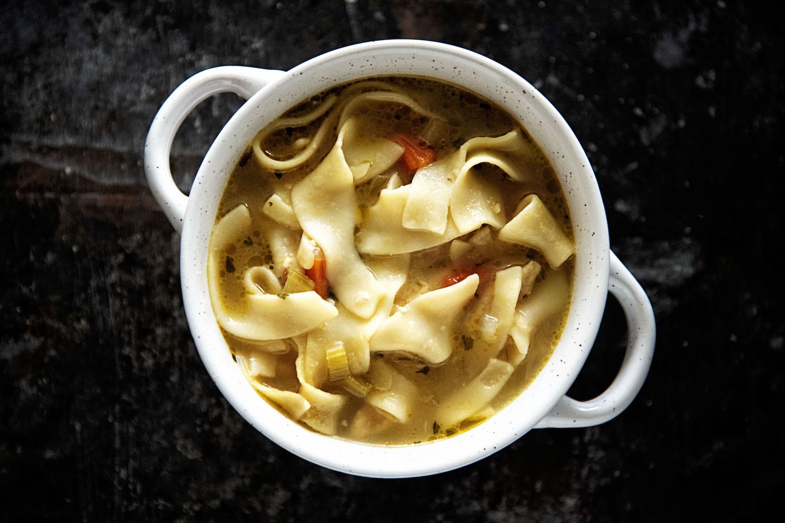 Bowl of Chickenless-Chicken Noodle Soup with spoon lifting up a noodle.