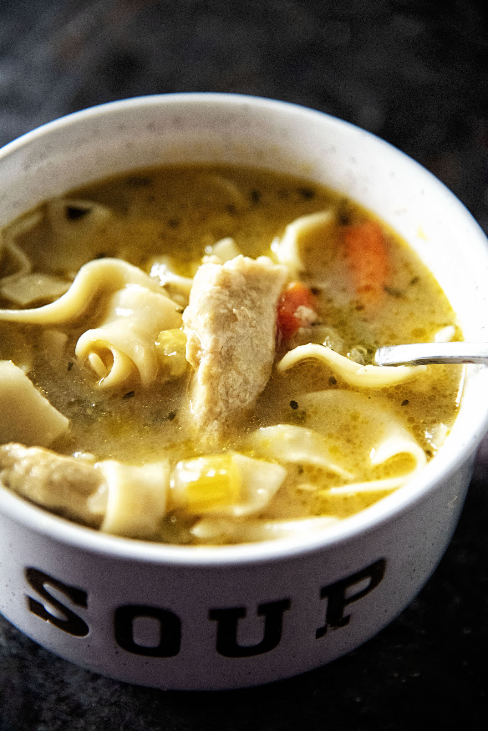 Upclose shot of Chickenless-Chicken Noodle Soup with spoon in bowl. 