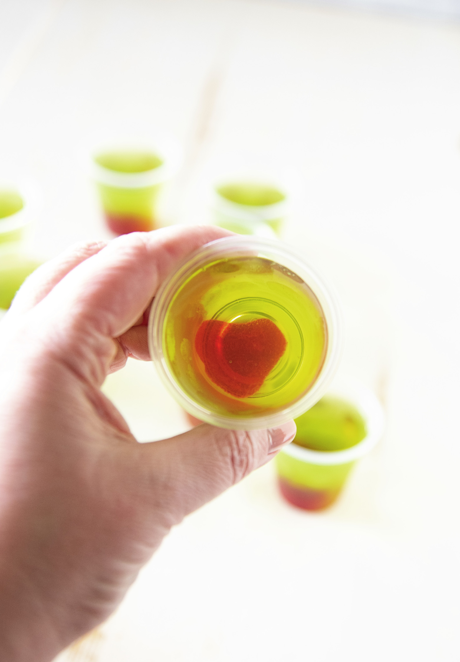 Hand holding a Grinch Jello Shot so you can see the heart in the middle of it. 