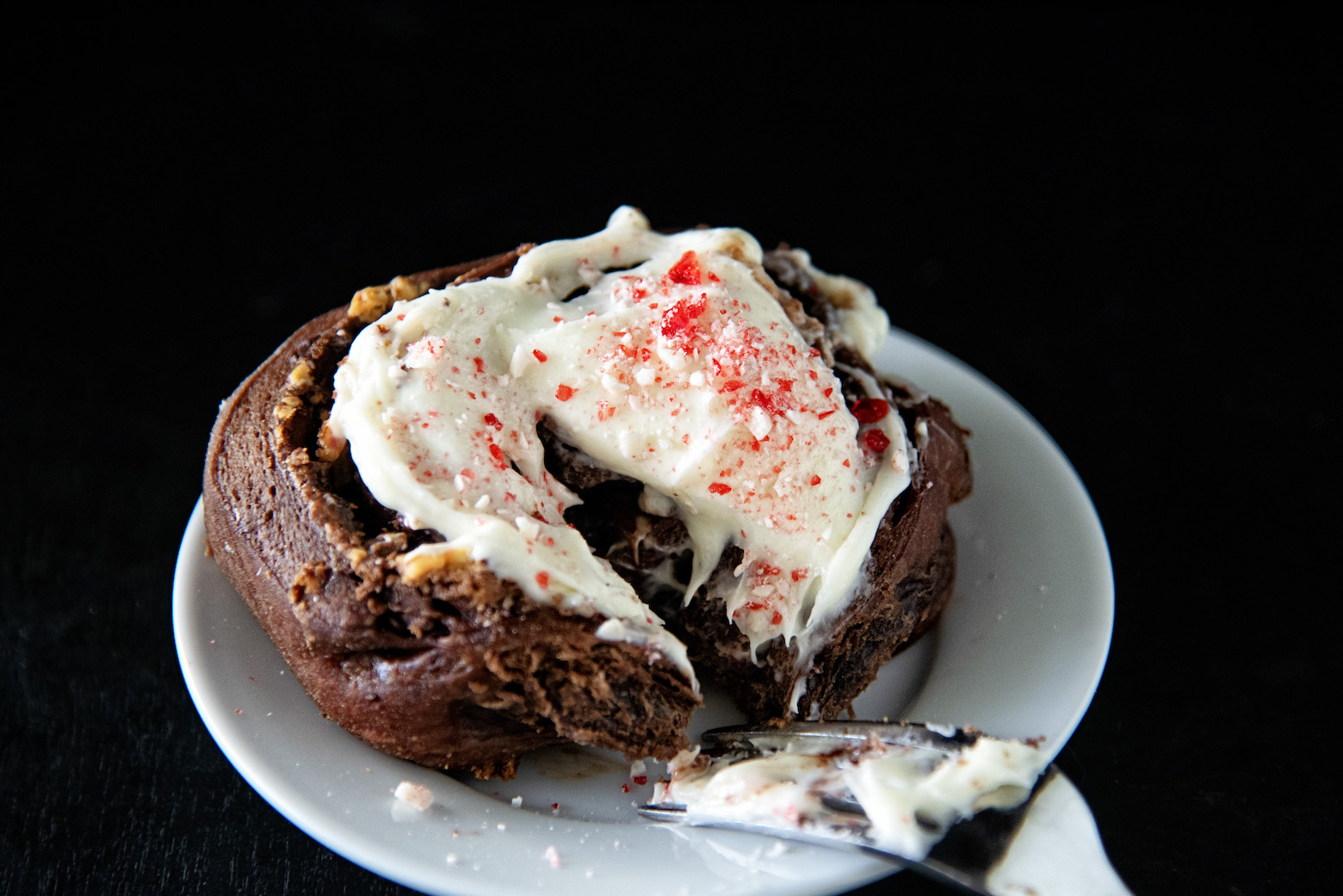 Single Peppermint Mocha Latte Sweet Roll on a plate with fork cutting it. 