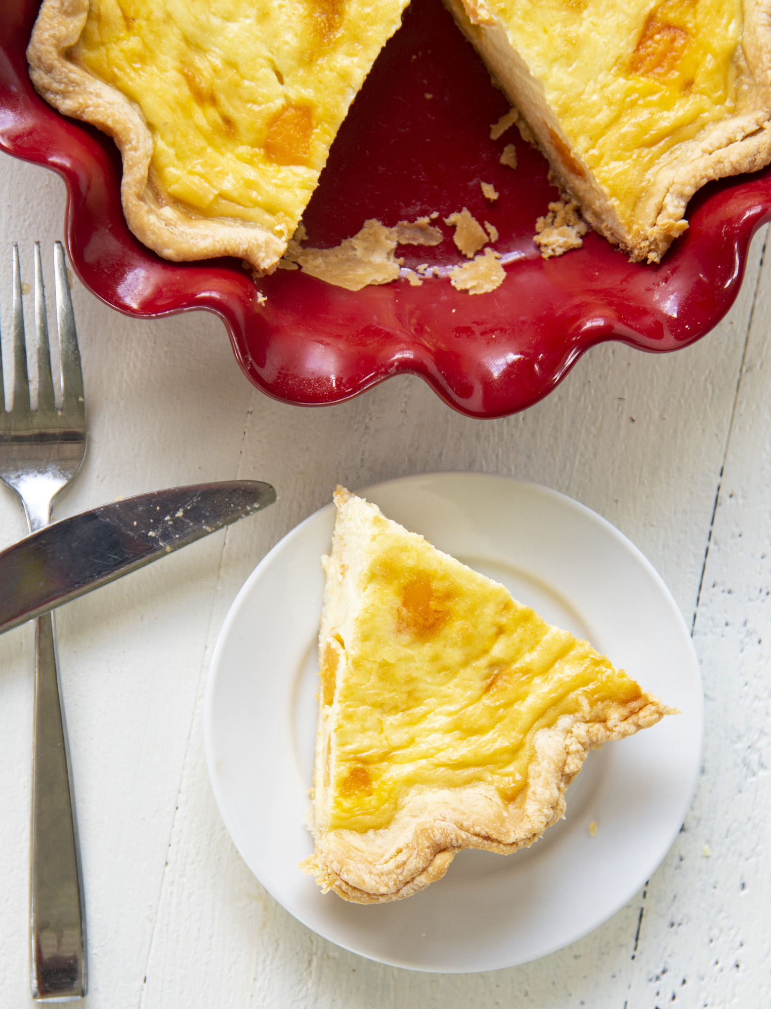 Overhead shot of Vegetarian Triple Cheddar Quiche slice on a plate with the pie pan in the photo. 