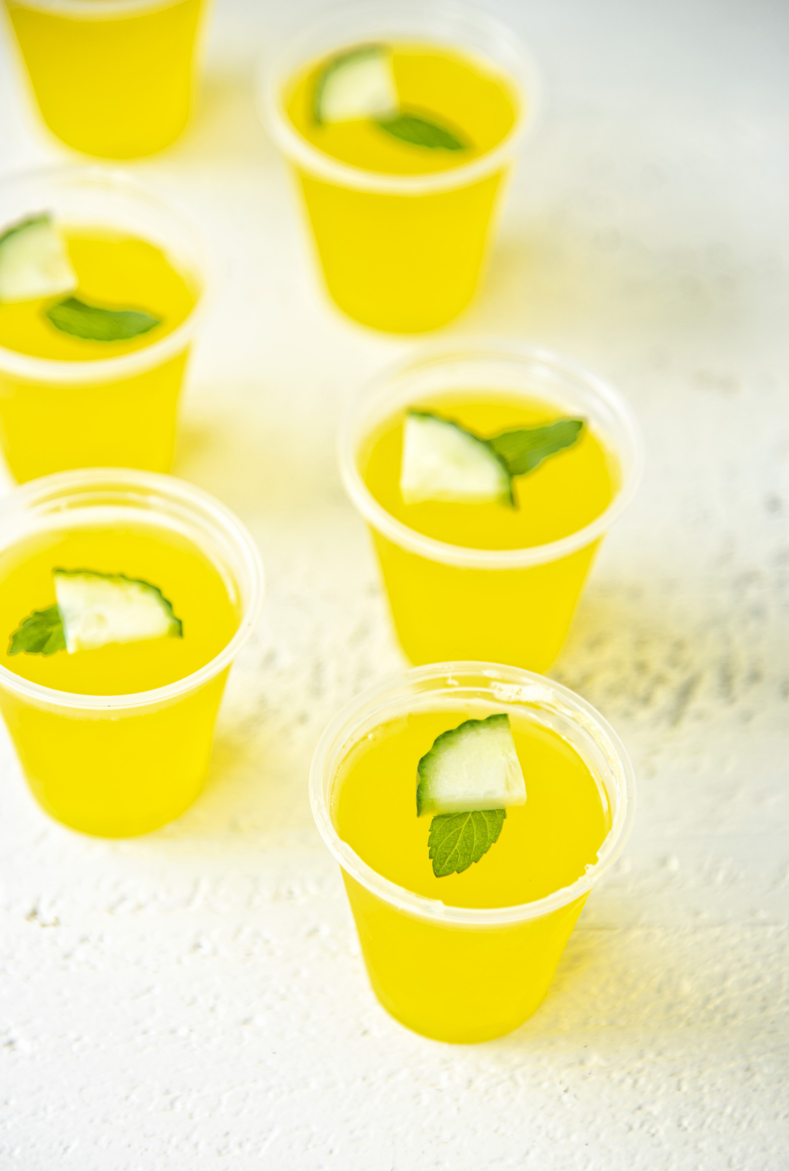 Several Cucumber Mint Lemonade Jello Shots with mint and cucumber garnish. Part of the Best Jello Shot Recipes rondup.