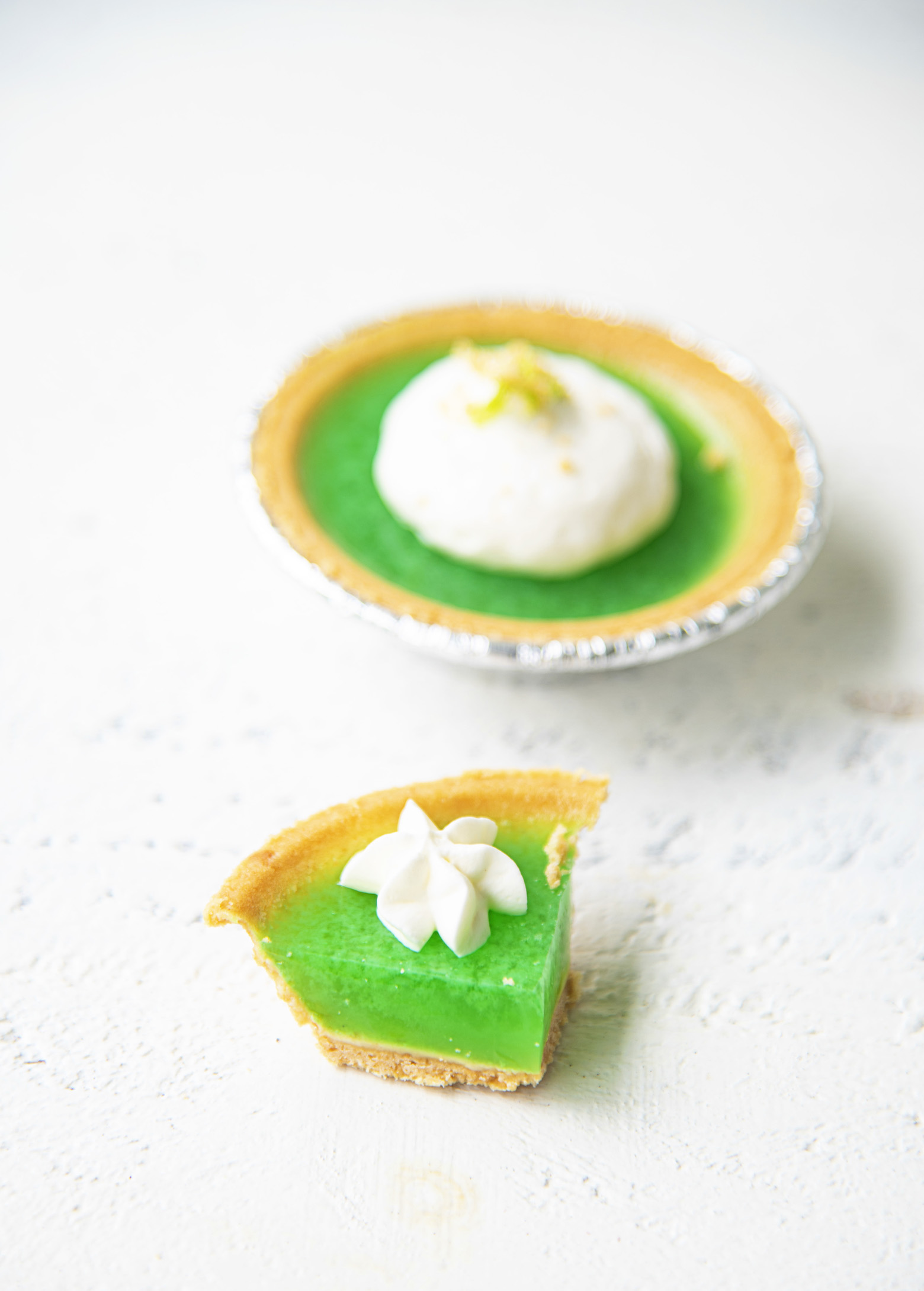 Slice of a Key Lime Pie Jello Shot with a whole one in the background. 