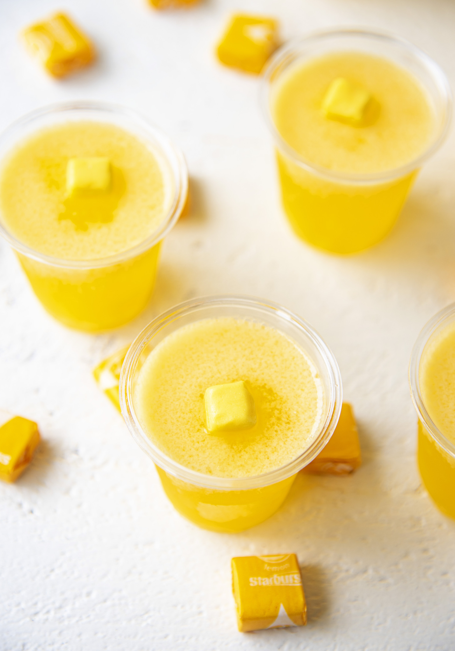 Three Yellow Starburst Jello Shots with focus on the first shot. 