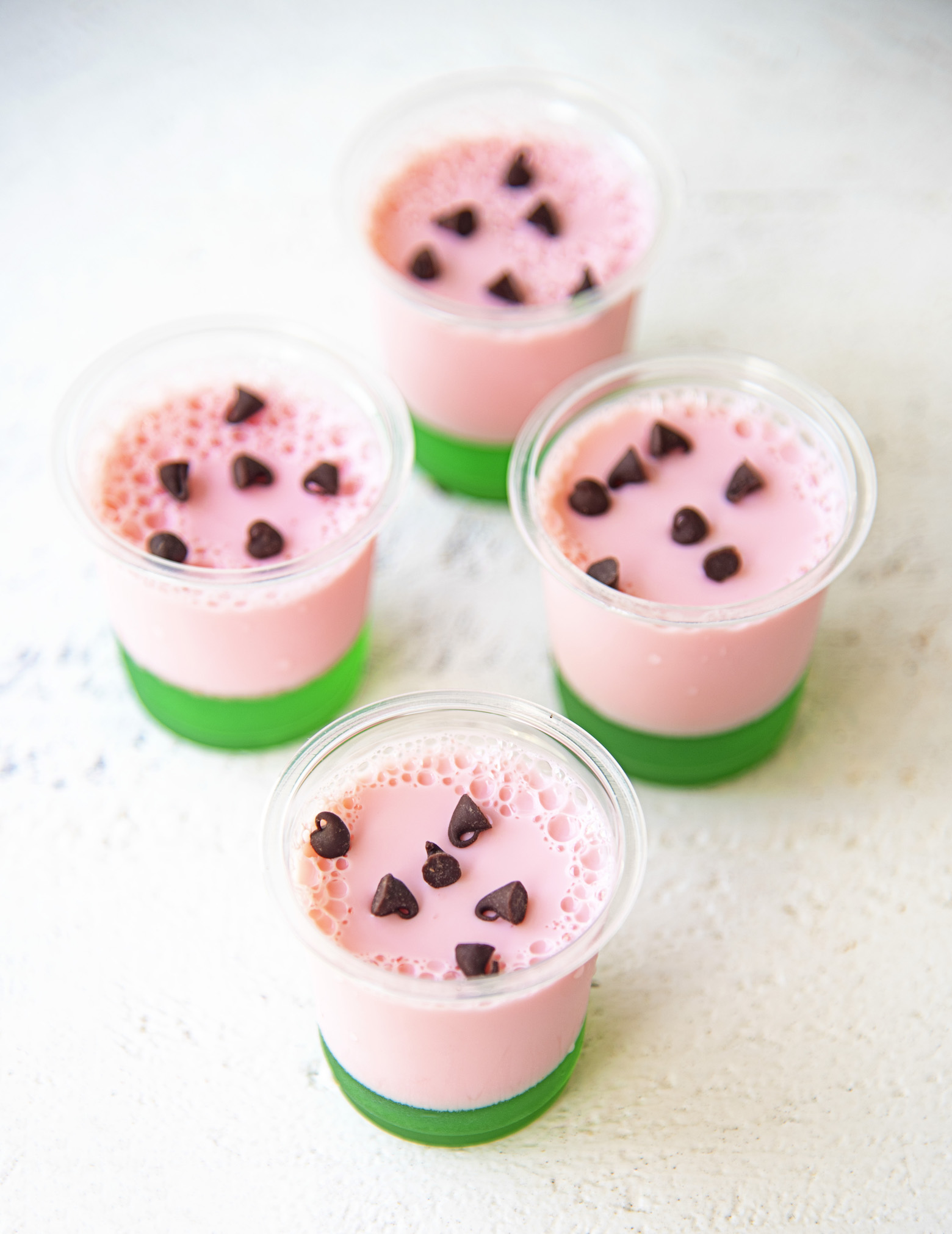 Four Watermelon Lime Jello Shots with focus on the first shot. 