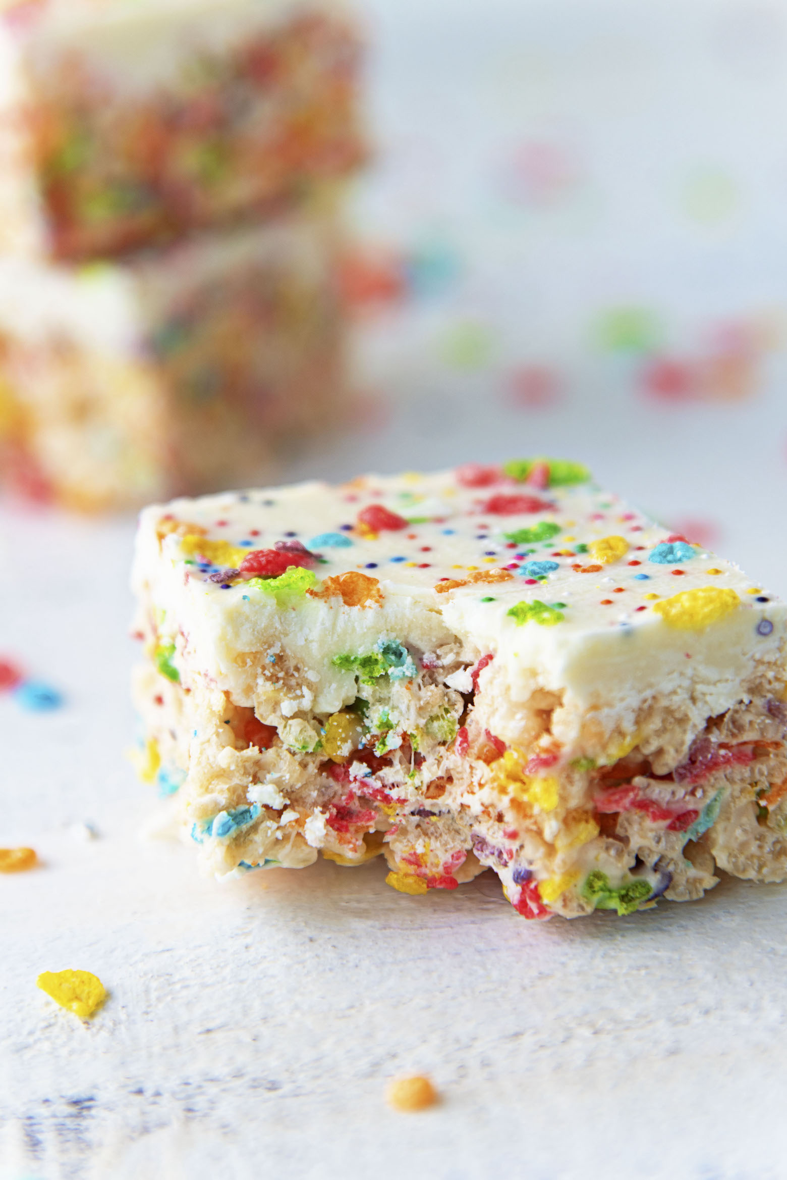 White Chocolate Fruity Pebbles Marshmallow Treats with bite out of them.