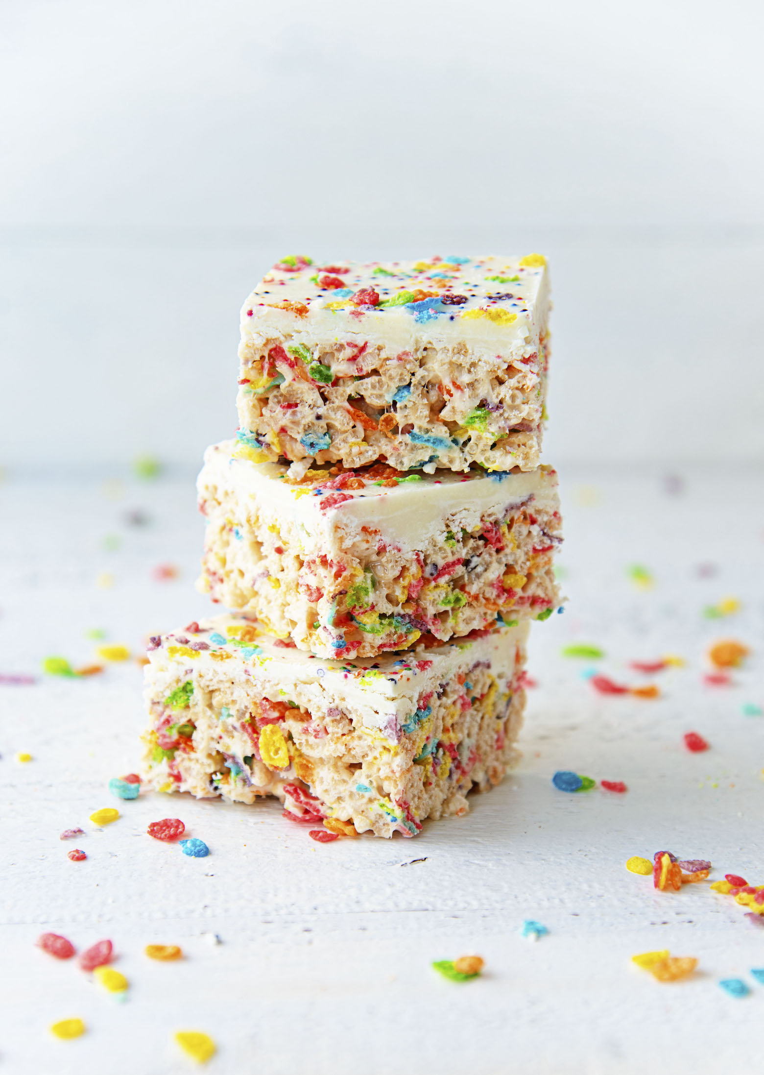 White Chocolate Fruity Pebbles Marshmallow Treats stacked in three.