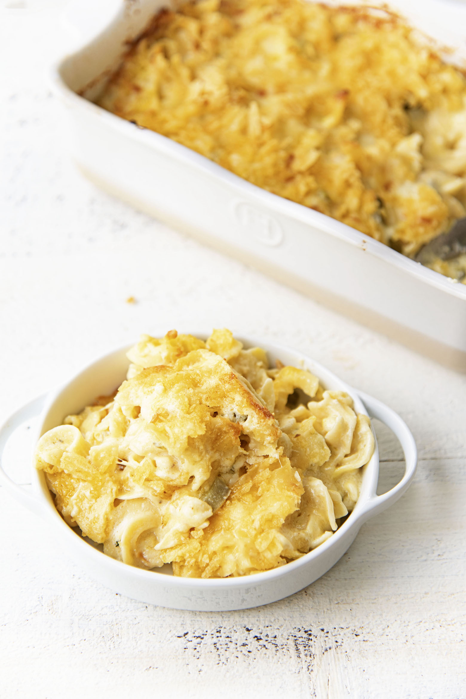 Picture of pasta in mac and cheese in rectangular baker with a bowl of pasta upfront. 