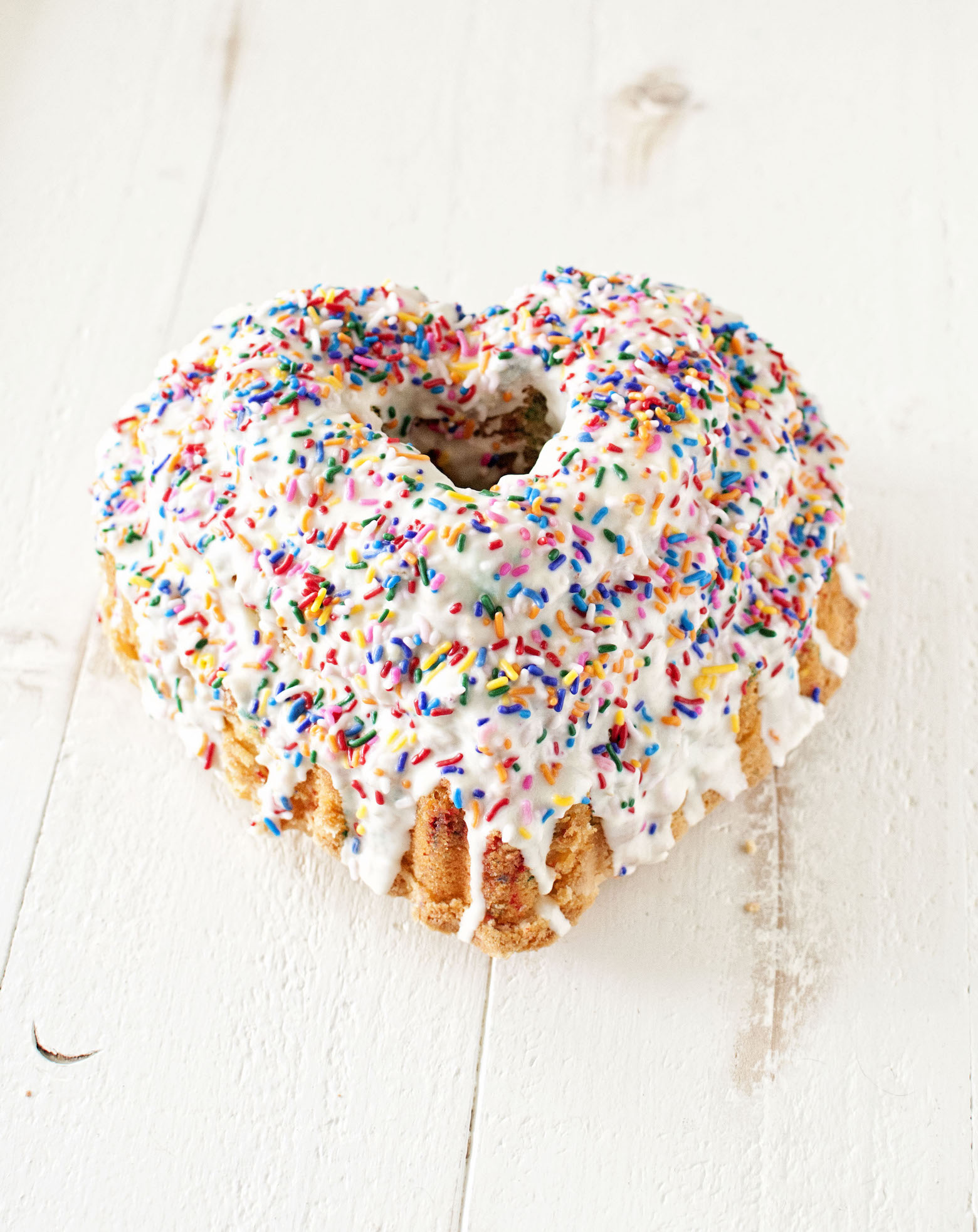 Side view of the pound cake with glaze and sprinkles dripping down. 