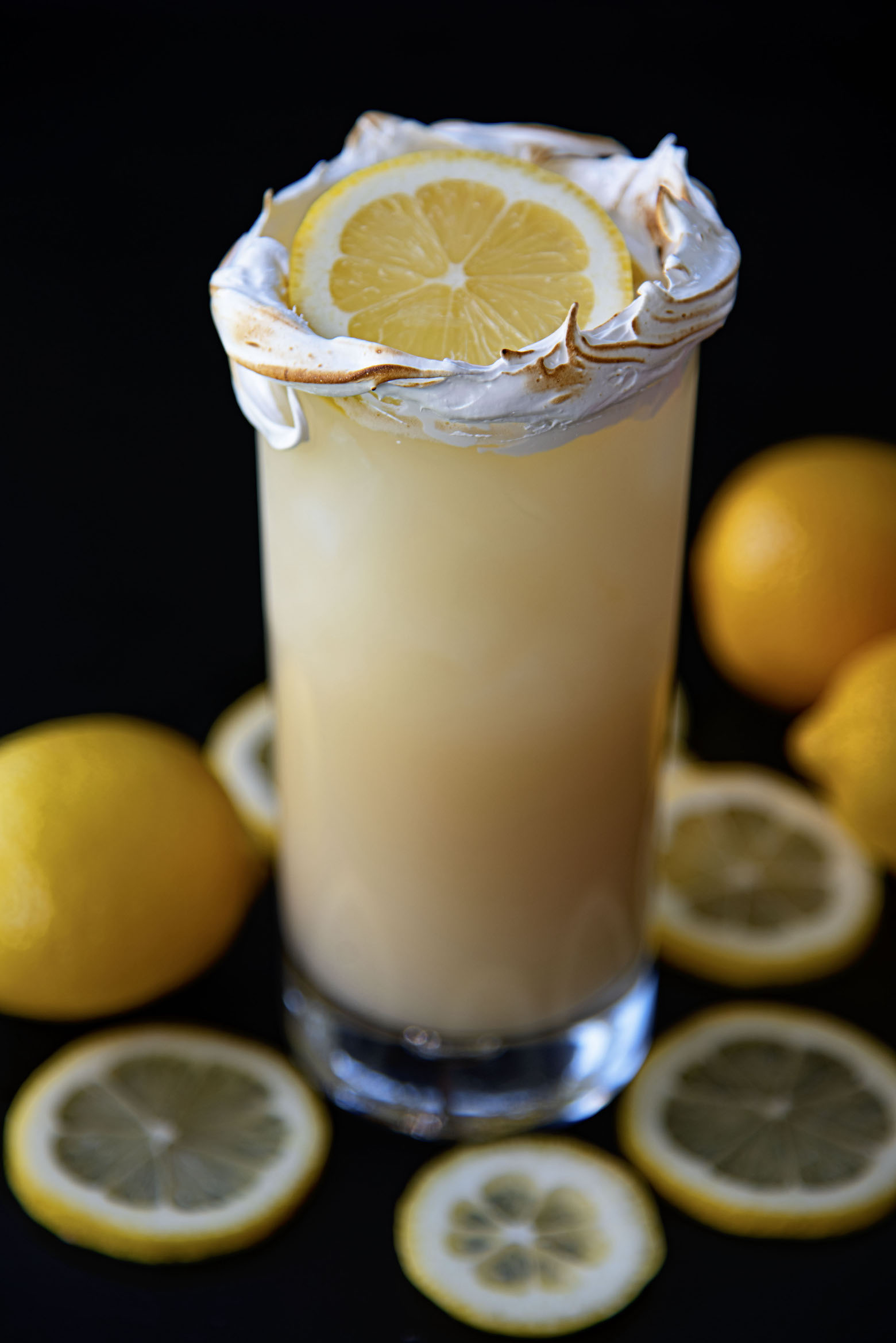 Full shot of the cocktail with fresh lemons around the glass. 