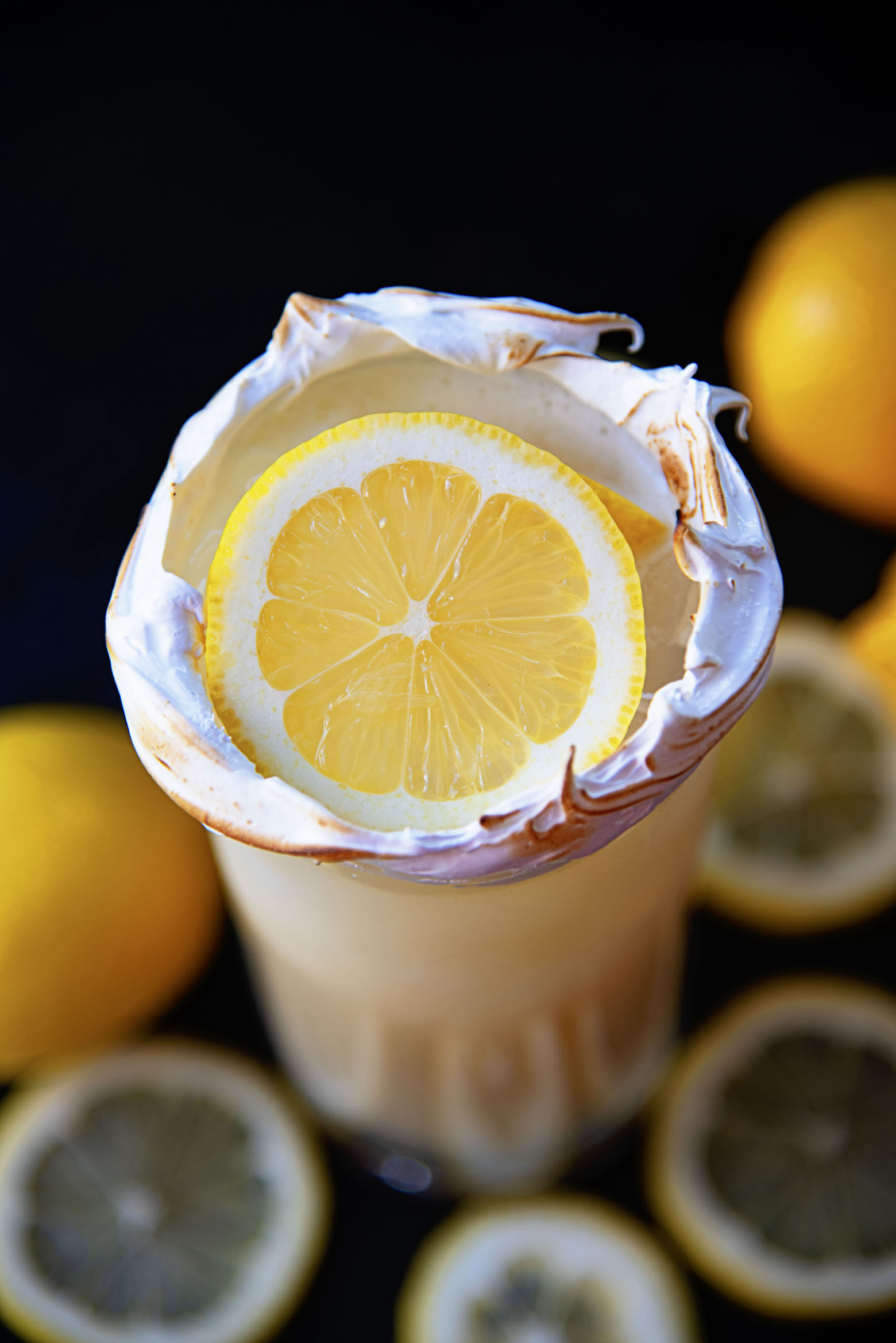 Overhead shot of cocktail with an up close shot of the lemon and meringue around the glass. 