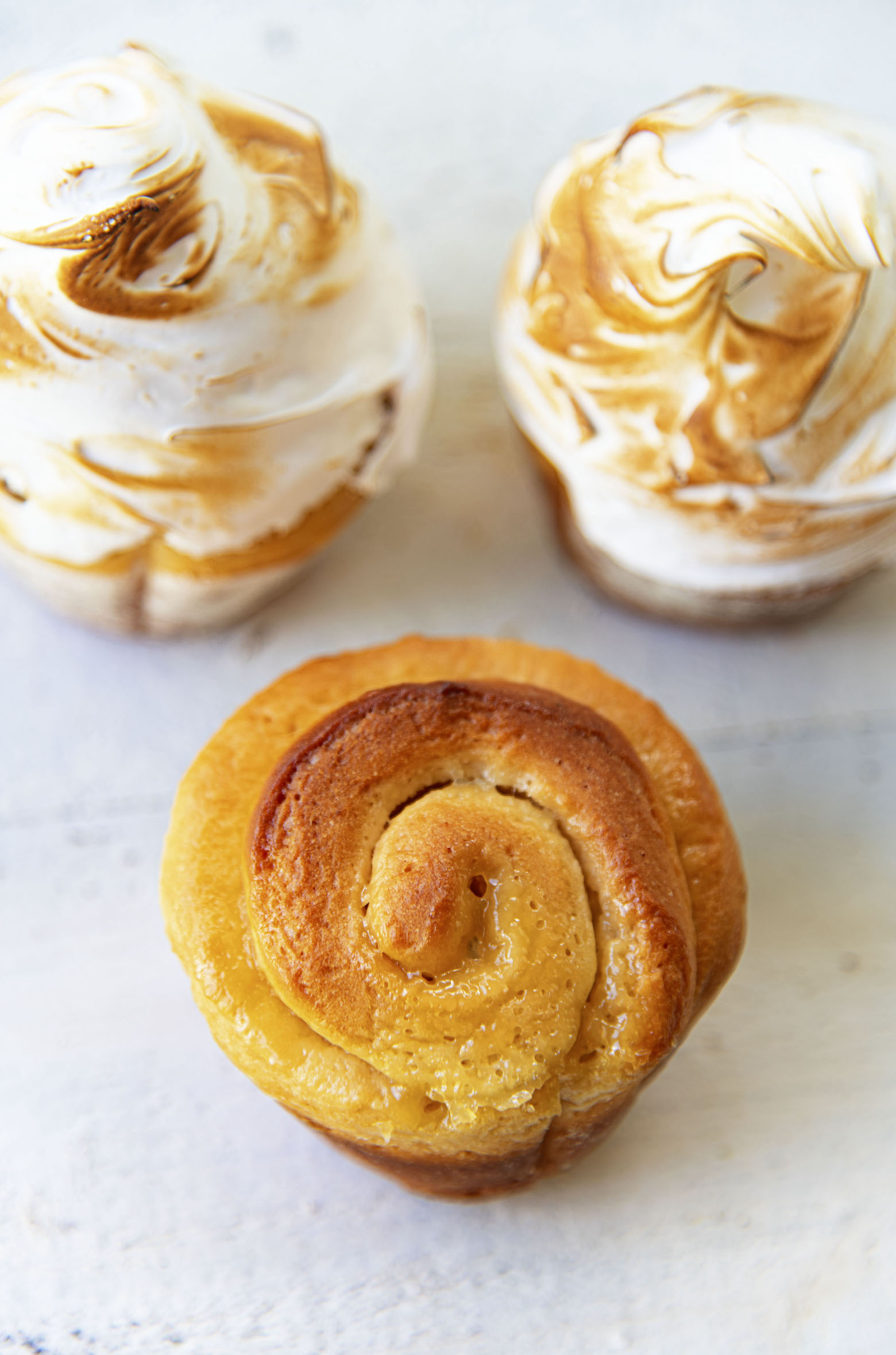 Three sweet rolls. Two with meringue on top and one plain so you can see the lemon curd. 