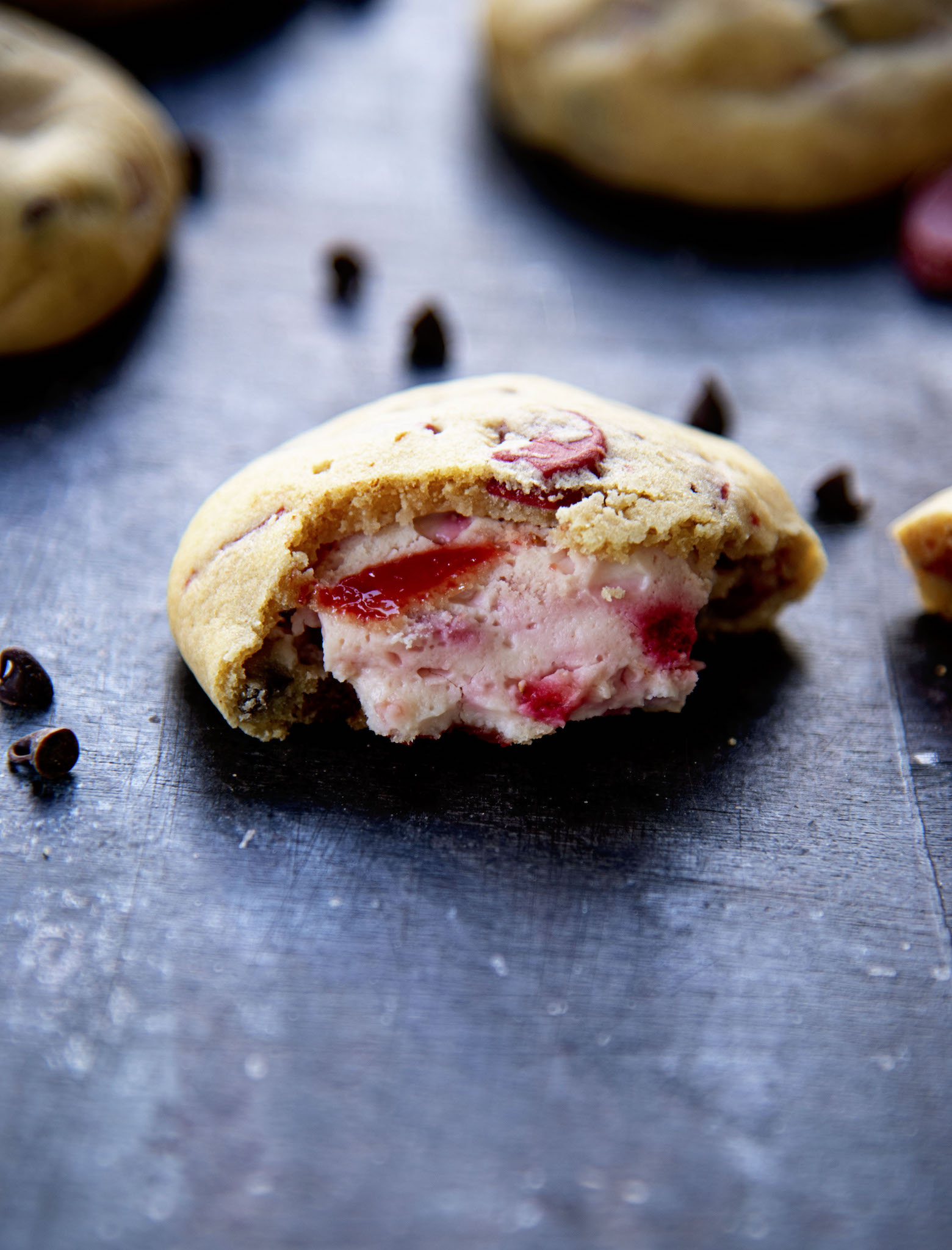 Half a cookie with strawberry cheesecake filling exposed.