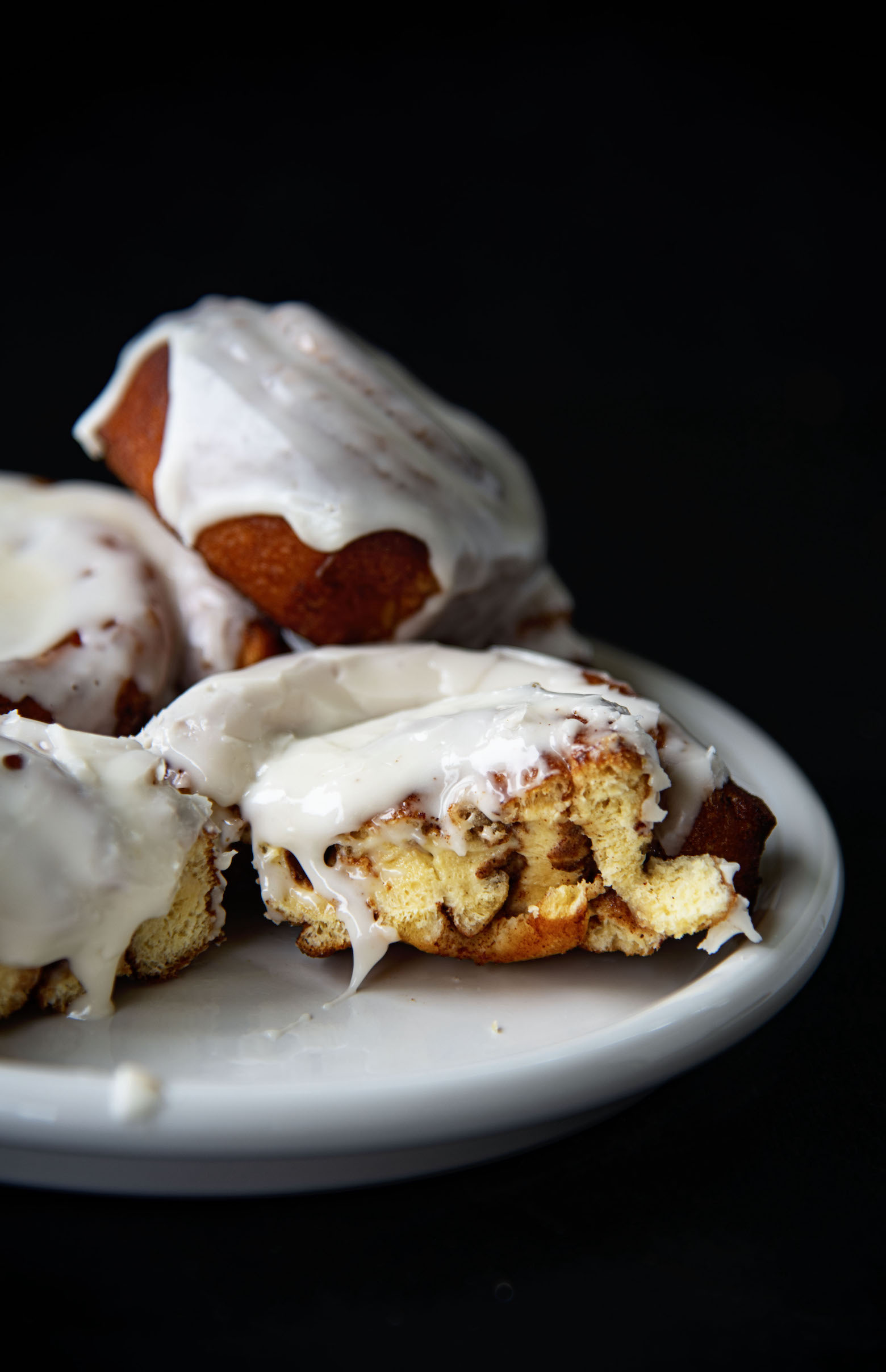 Deep Fried Cinnamon Rolls on a plate. One roll has a bite taken out of it. 