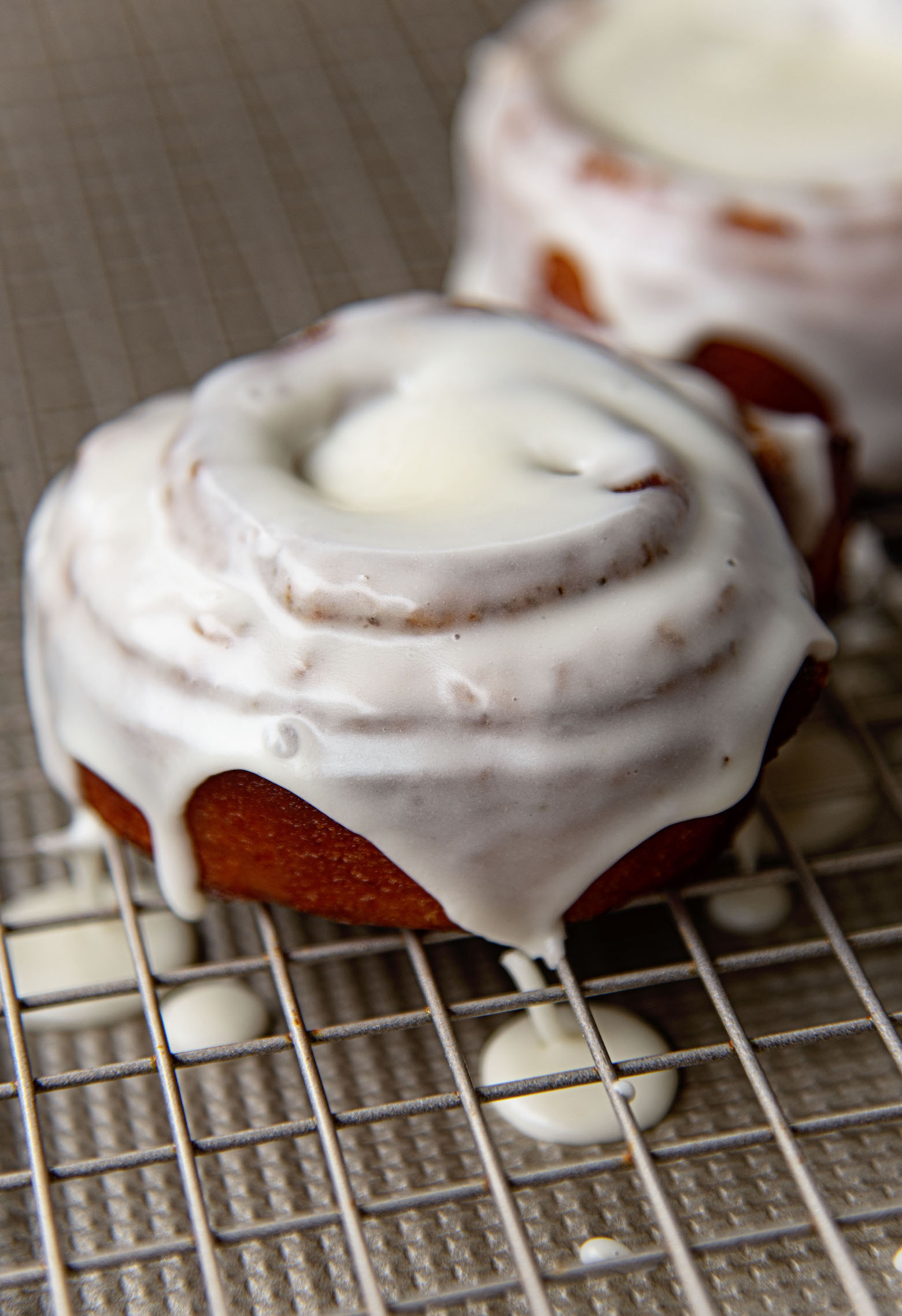 Deep Fried Cinnamon Rolls on wire rack with dripping glaze.