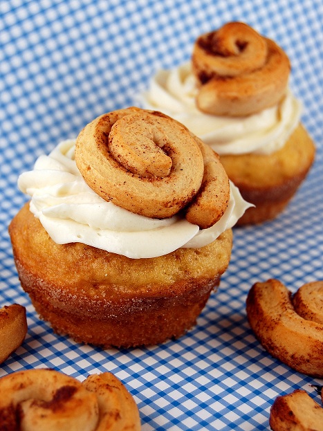 Two cinnamon roll cupcakes with mini cinnamon rolls around them. 