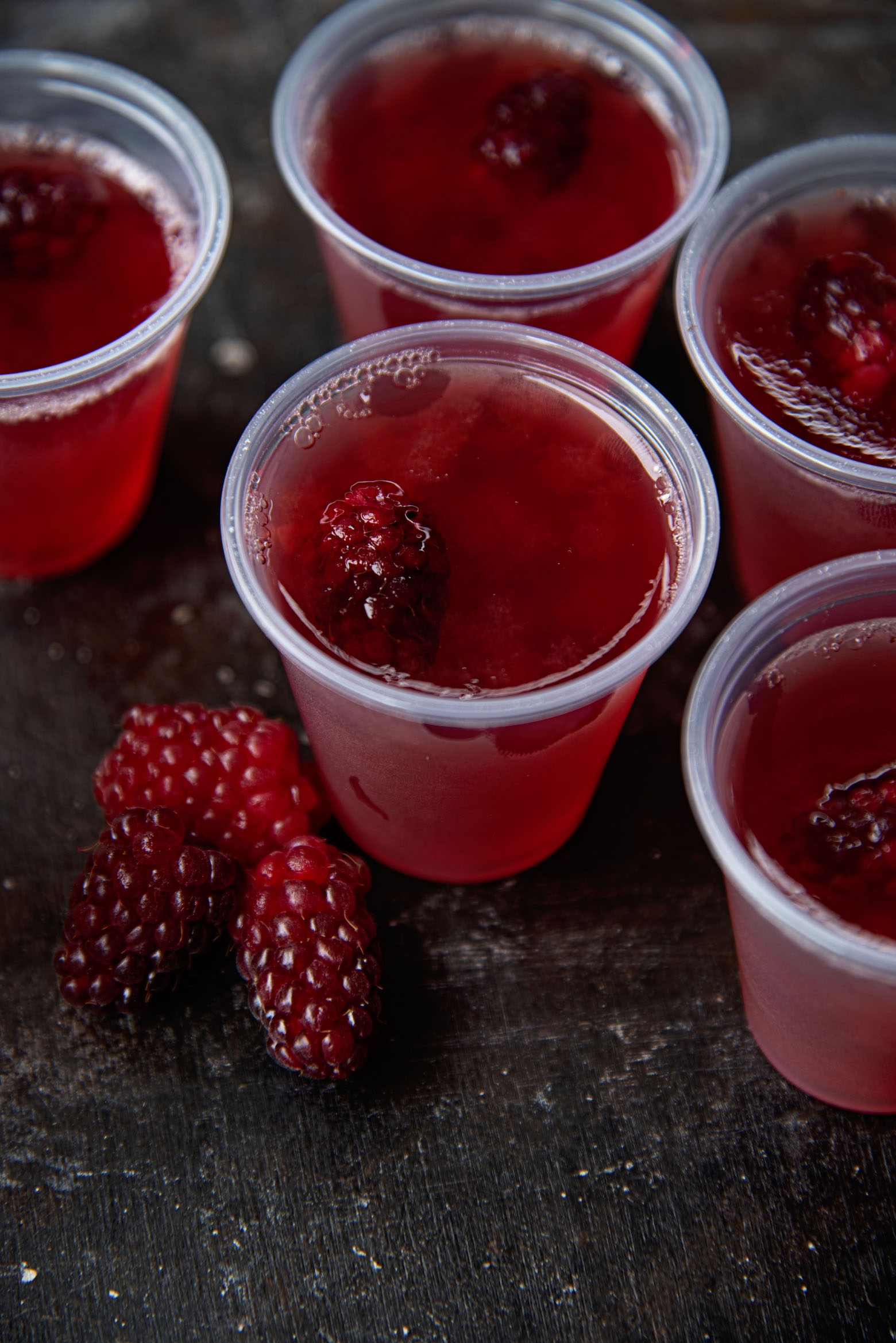 Overhead shot of Fresh Berry Peach Jello Shots with fresh berries in them and to the side of the shots. 