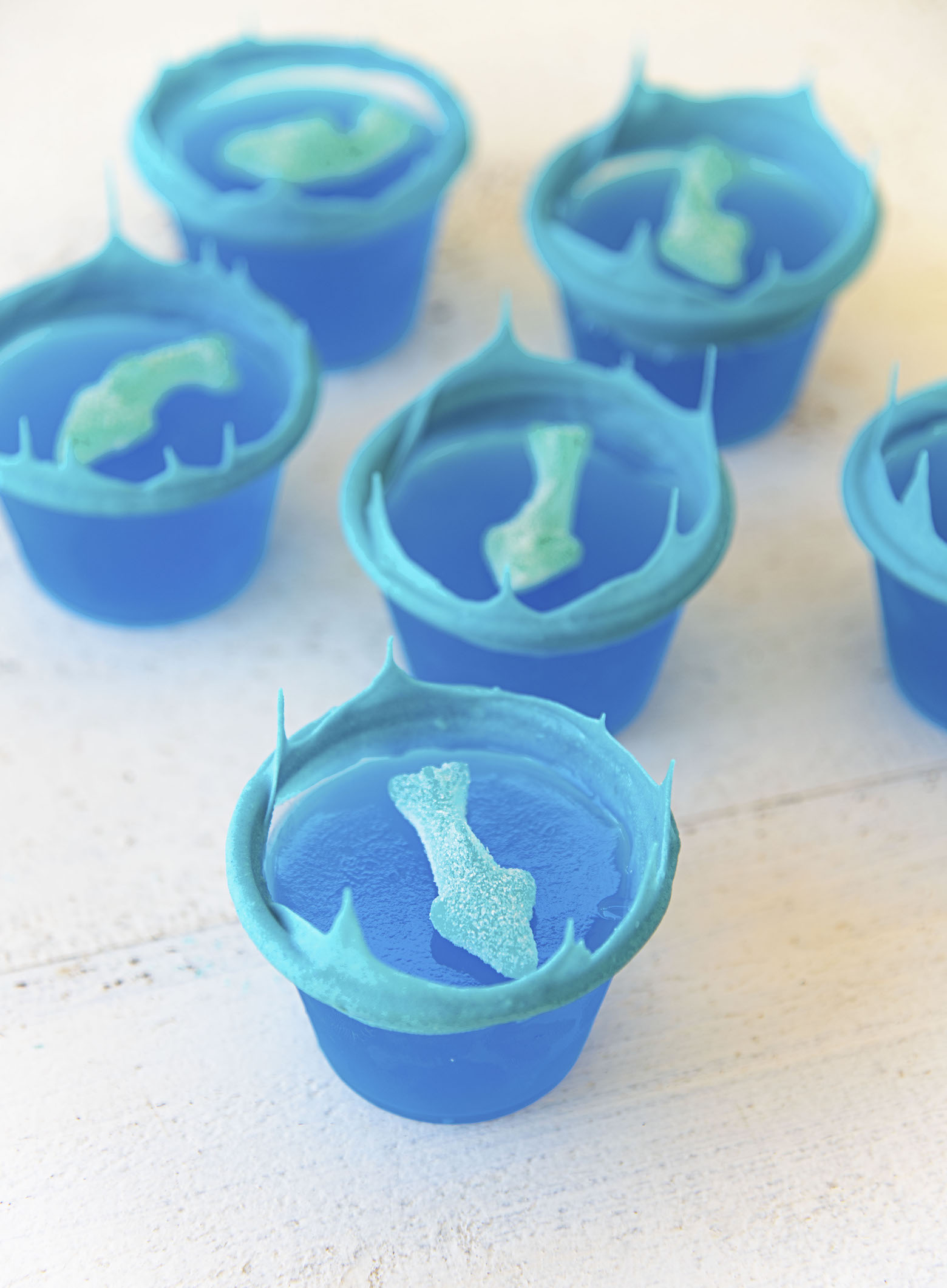 Several Ocean Water Jello Shots with blue white chocolate waves and gummy sharks. 