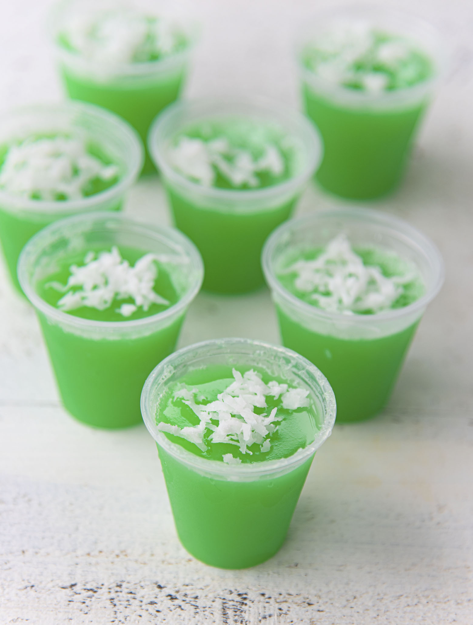 A bunch of Lime Coconut Jello Shots grouped together with shredded coconut on top. 