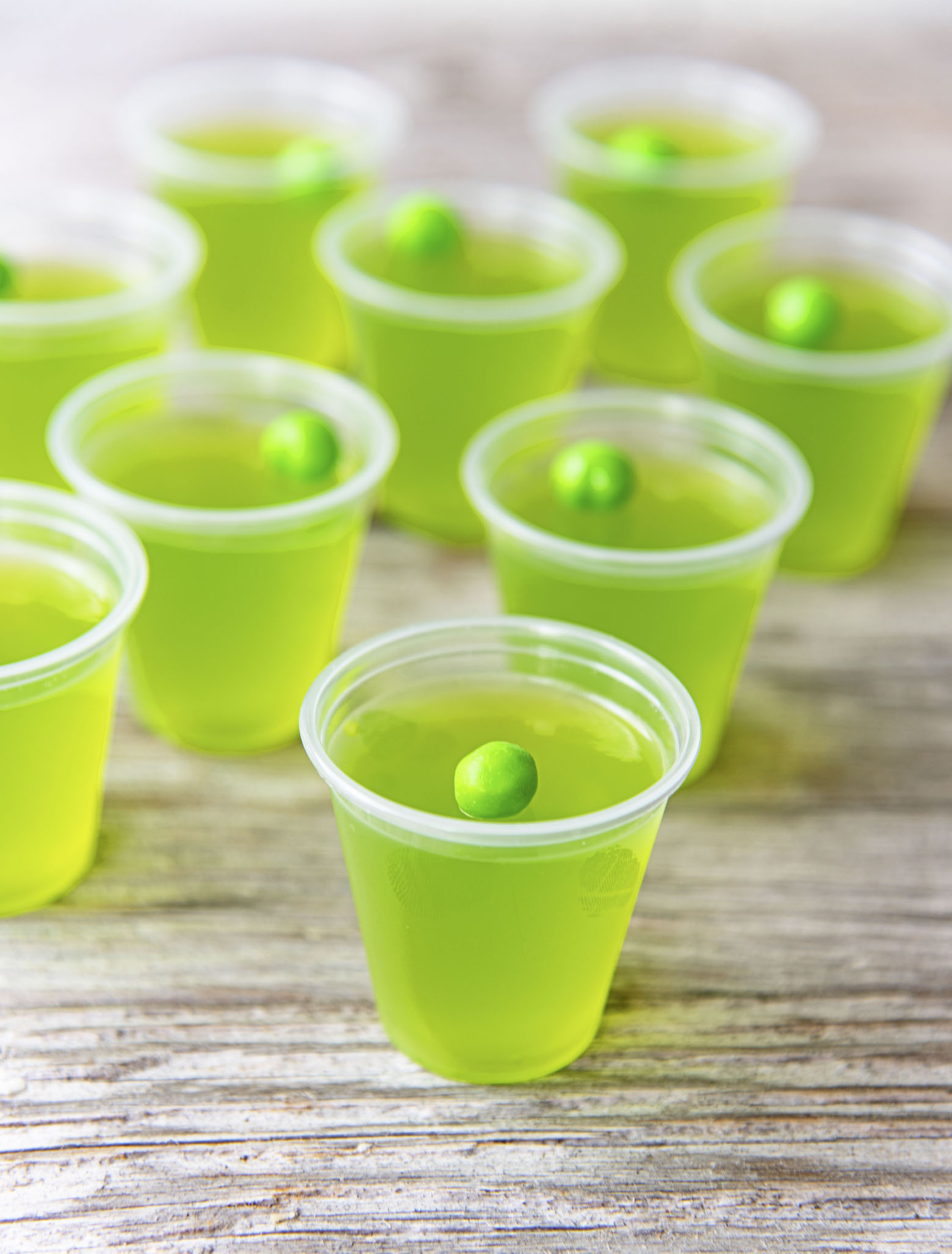 A bunch of Apple Cider Moscow Mule Jello Shots with mini green apple candies on top as garnish. 