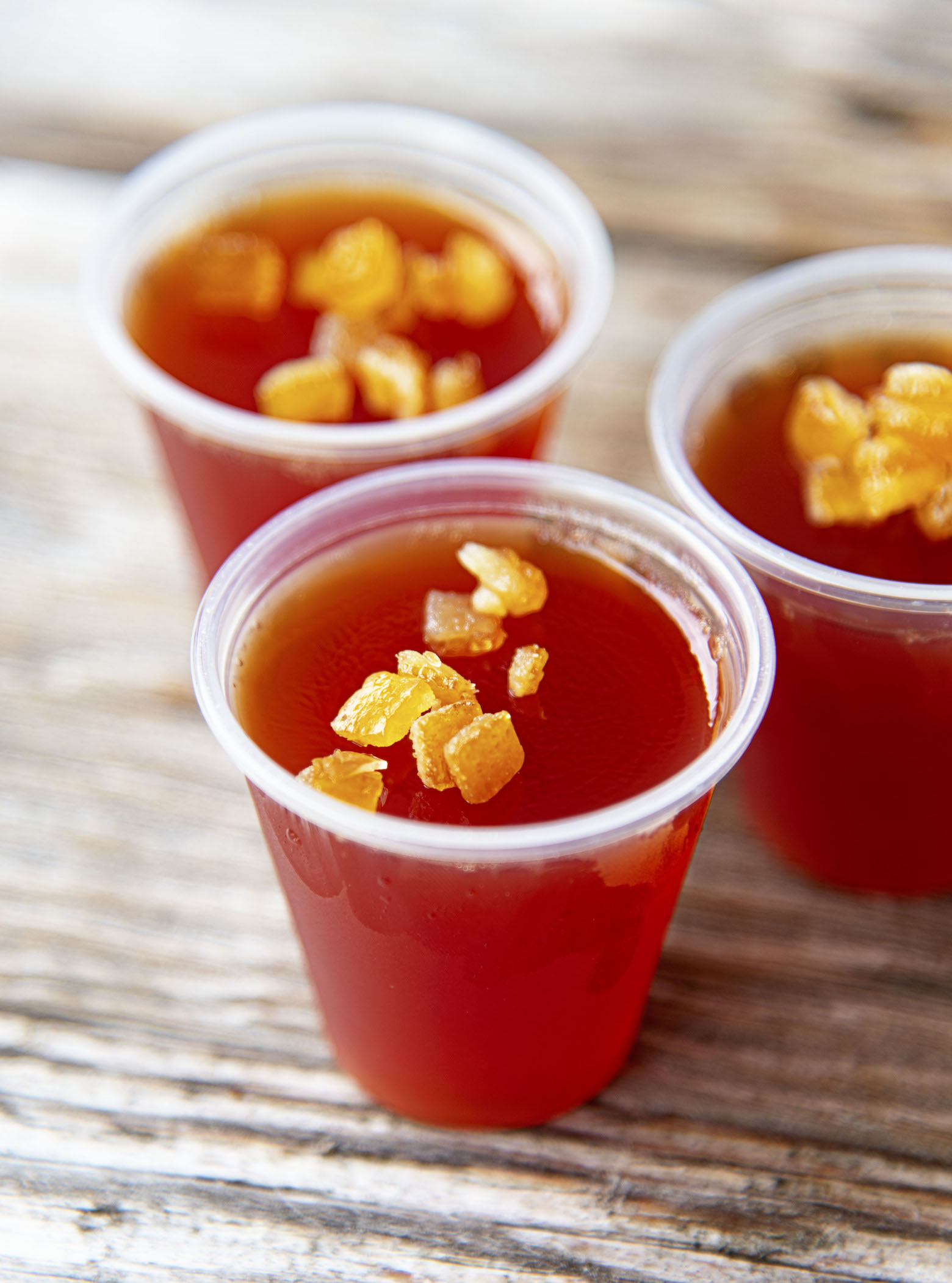 Three Harvest Jello Shots clustered together with candied orange peel pieces on top as garnish. 