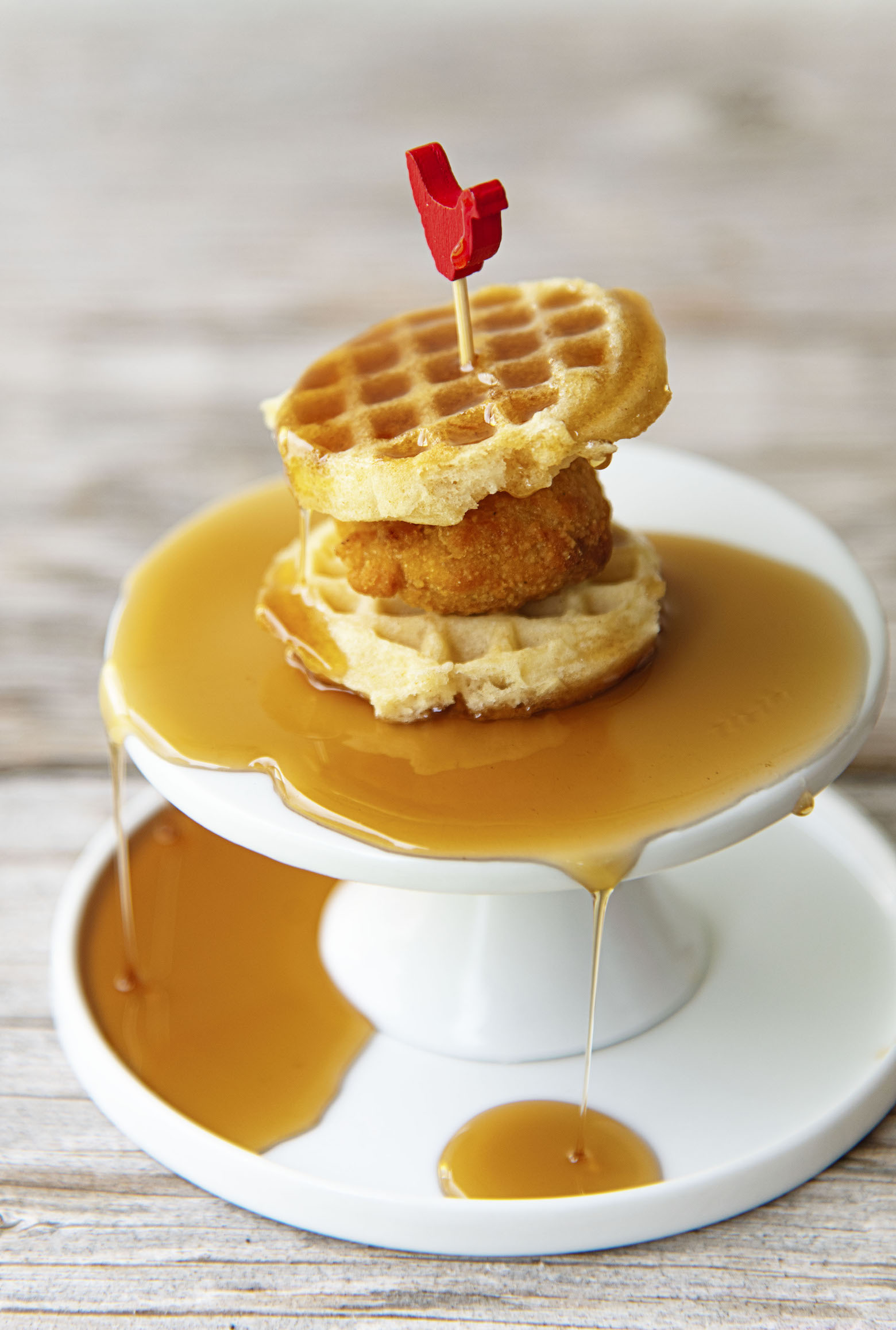 Single Mini Chick’n and Waffle on a mini pedestal covered in syrup. 